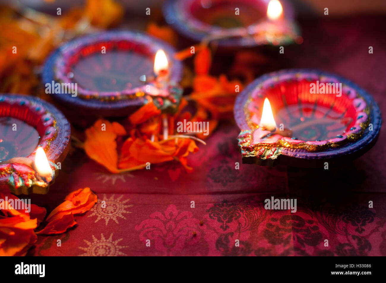 Diya lampade accese durante il Diwali celebrazione con fiori e dolci in background Foto Stock