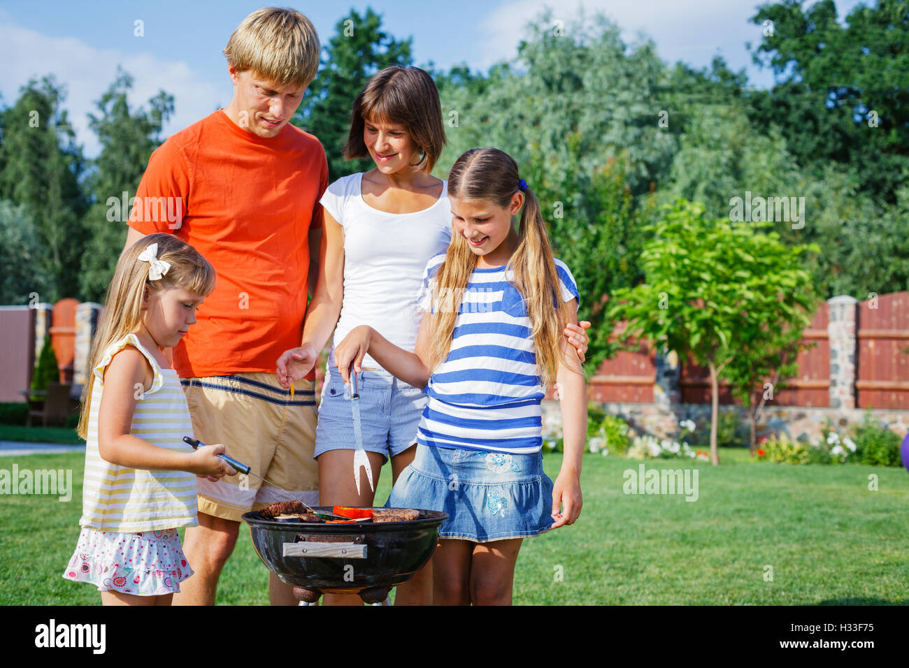 La famiglia felice con barbecue Foto Stock