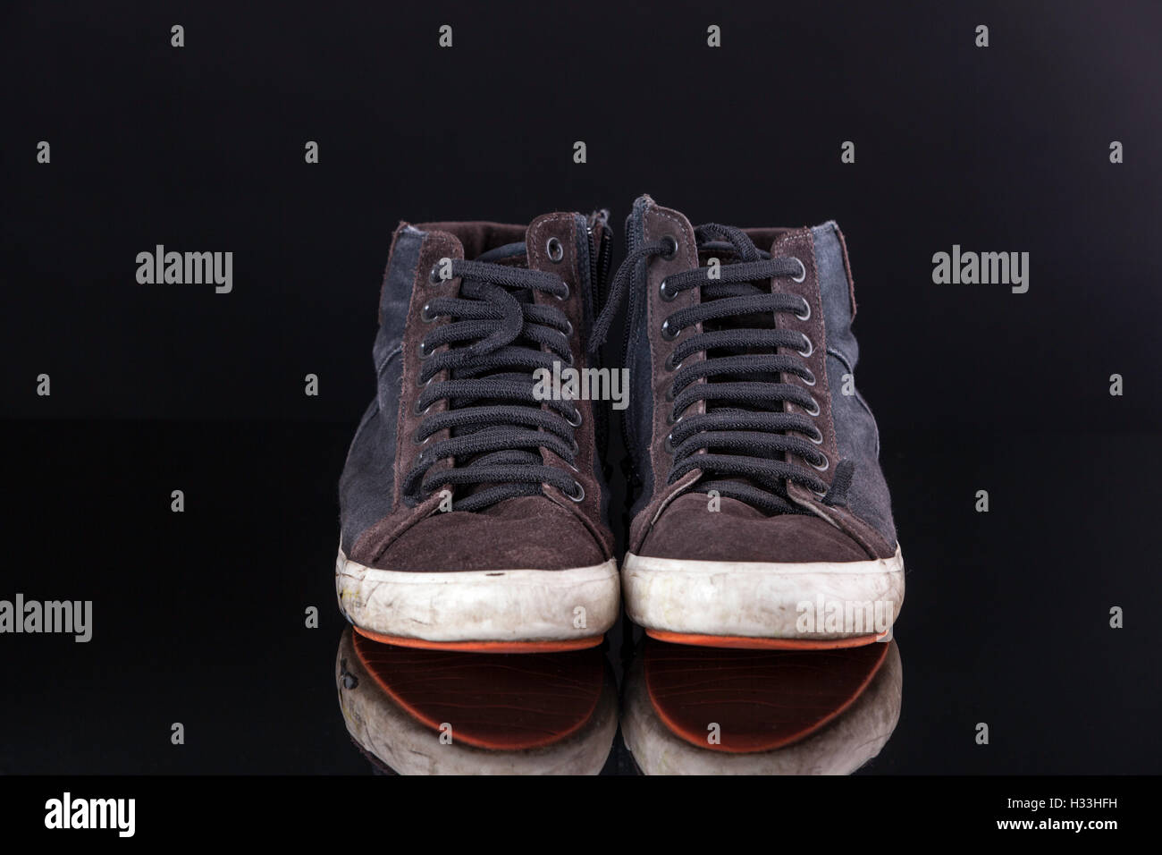 Coppia di vecchi nero scarpe palestra shot nero su sfondo riflettente. Foto Stock