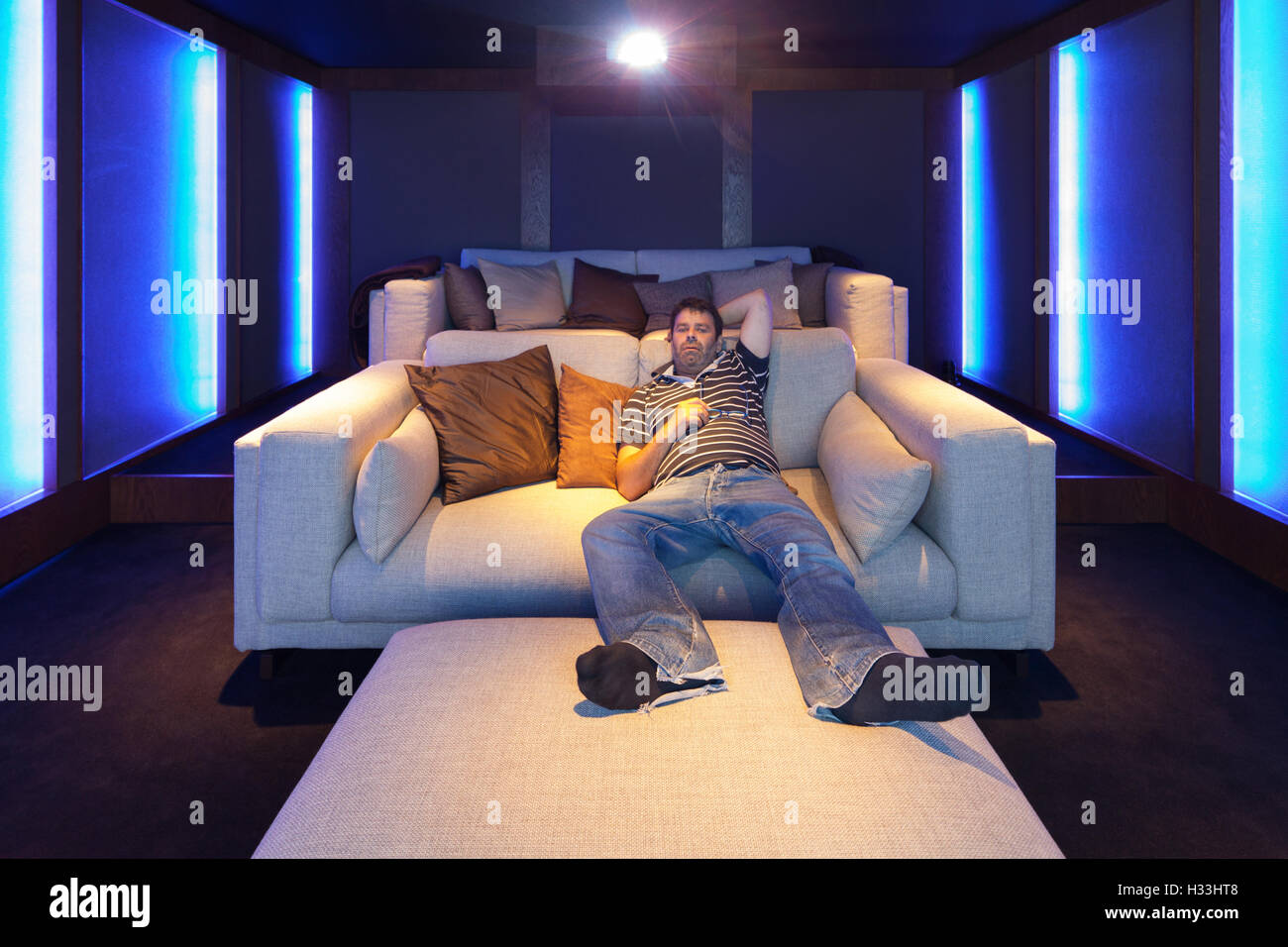 L'uomo la visione di un filmato nell'home theatre, interni di lusso Foto Stock