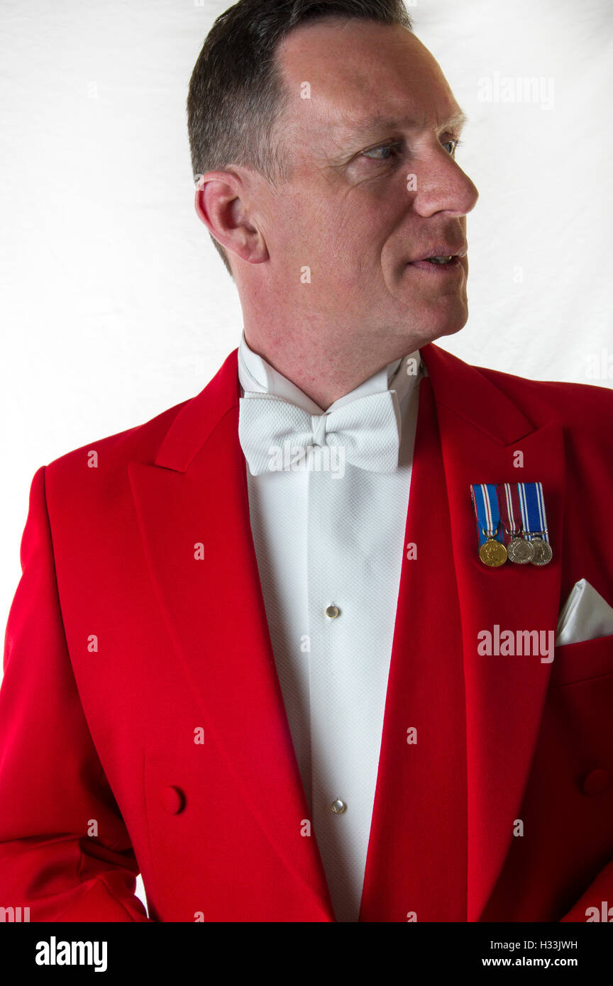 Toastmaster contro uno sfondo bianco nelle tradizionali giacca rossa con i guanti bianchi e medaglie Foto Stock