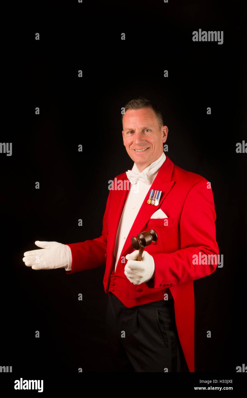 Toastmaster contro uno sfondo nero nelle tradizionali giacca rossa con i guanti bianchi e medaglie e fazzoletto Foto Stock