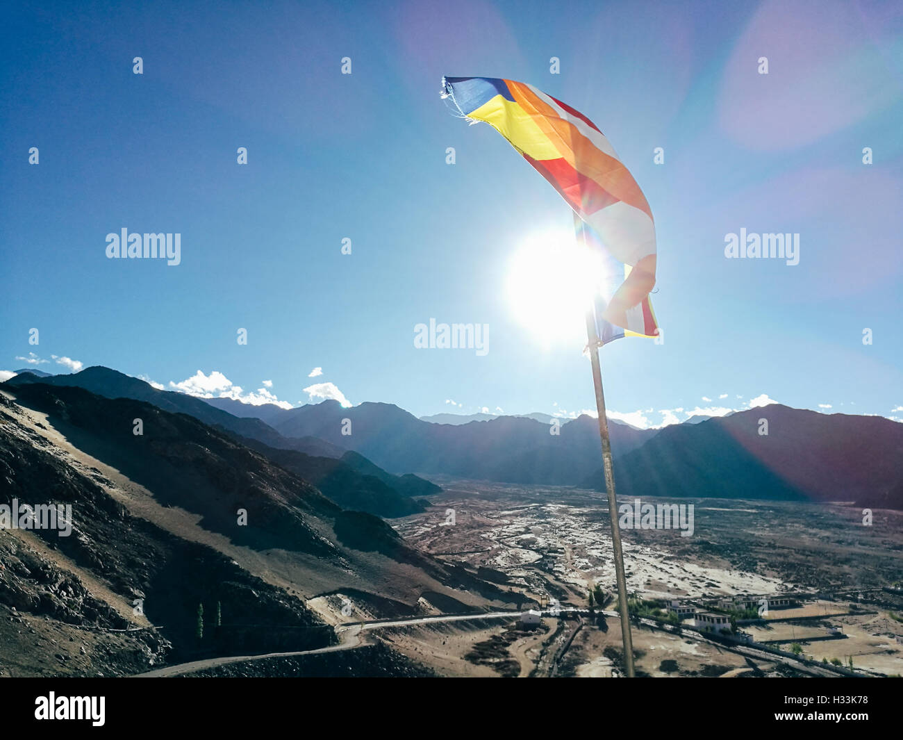 Una sola preghiera buddista bandiera in sei colori svolazzanti nella regione di montagna contro la luce del sole. - Le bandiere colorate possono offrono Foto Stock