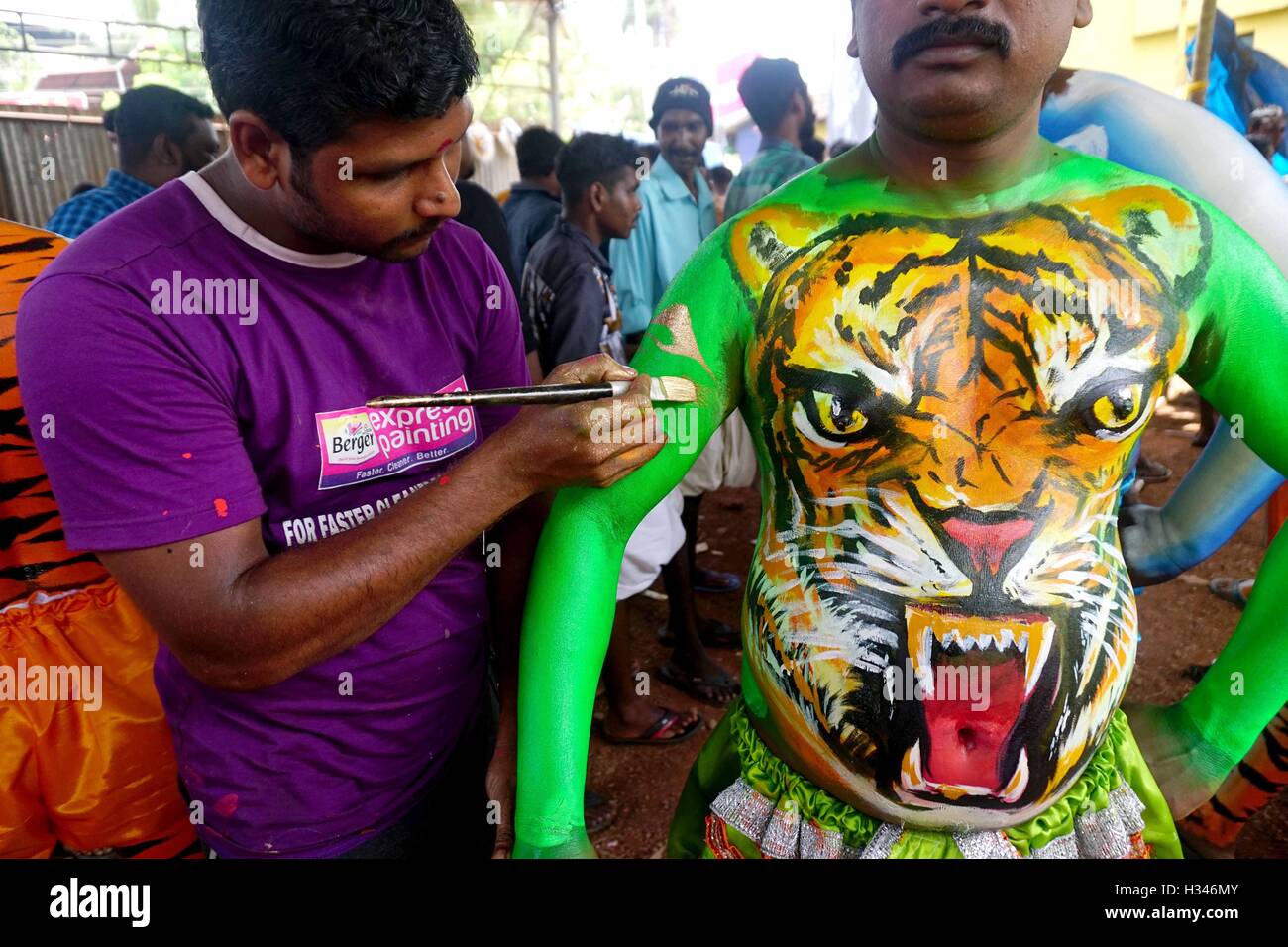 Un ballerino qualificato ottiene il suo corpo verniciato nei colori tiger si prepara a partecipare al famoso Pulikali Thrissur Kerala Foto Stock