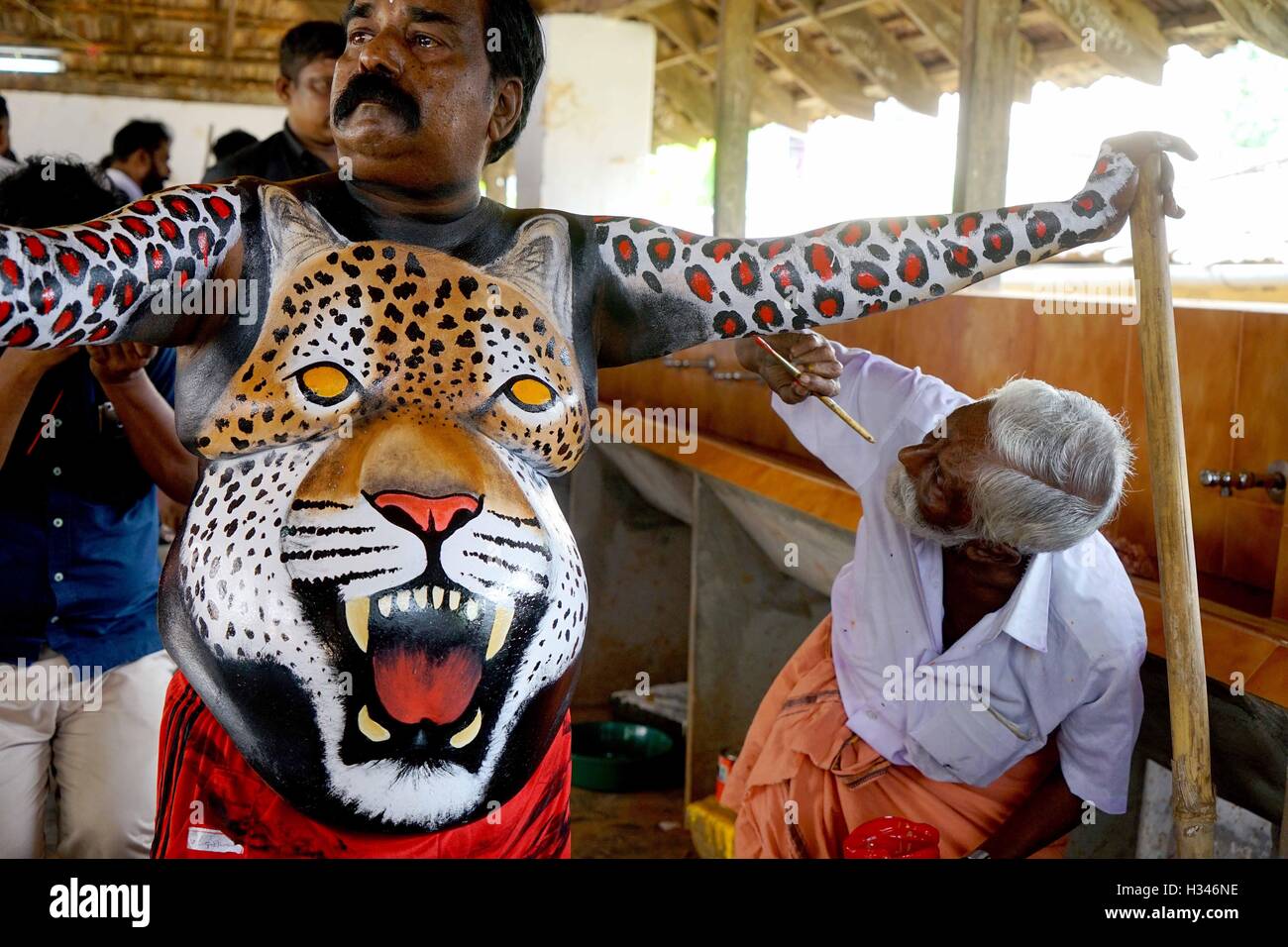 Un ballerino qualificato ottiene il suo corpo verniciato nei colori di una tigre si prepara a partecipare famoso Pulikali Thrissur Kerala Foto Stock