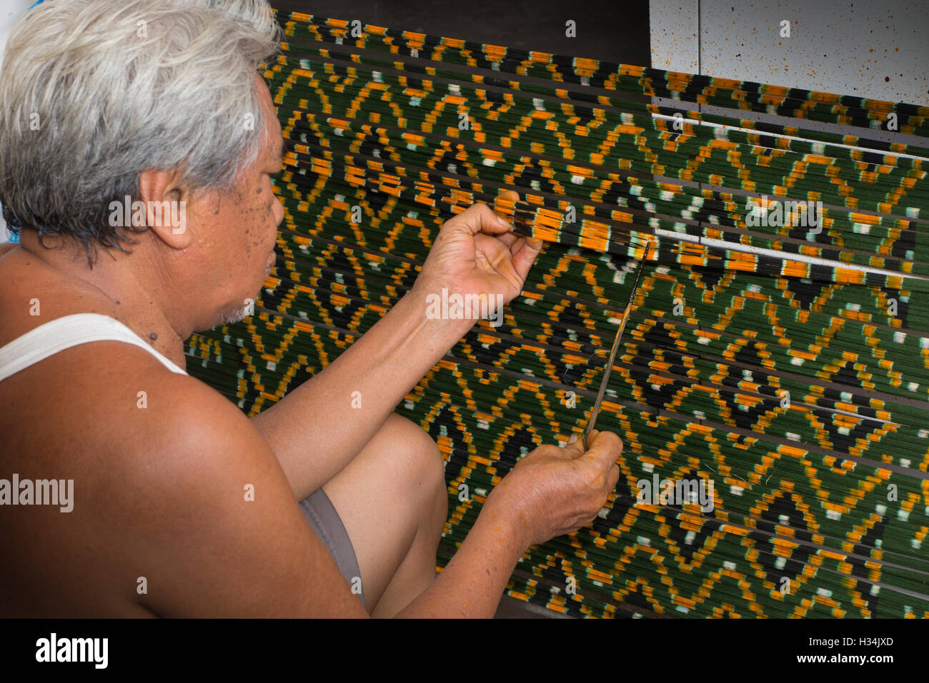 Indonesia, Bali, Singaraja, Pertenunan Berdikari atelier di tessitura, lavoratore mano morente trama ikat mostrando il modello di thread Foto Stock