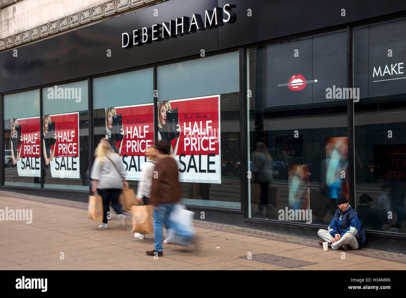 Fuori fuoco sfocato shoppers, gente camminare figure passando a metà prezzo vendita autunnale segni in negozio Debenhams, Manchester, Regno Unito. Vendita e riduzioni, offerte & offerte, articoli in liquidazione, sconto, Prezzo, Promozione, retail business in negozio Debenhams. Foto Stock