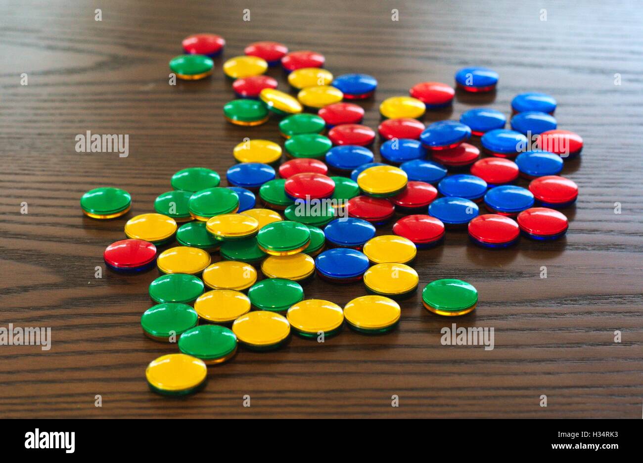 Colorati i contatori di gioco sparsi in un finto legno tavolo. Foto Stock