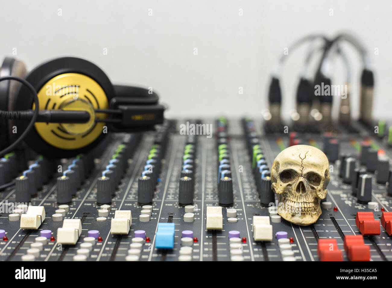 Cranio umano in appoggio su di un mixer audio. Sullo sfondo delle console mixer e cuffie. Foto Stock