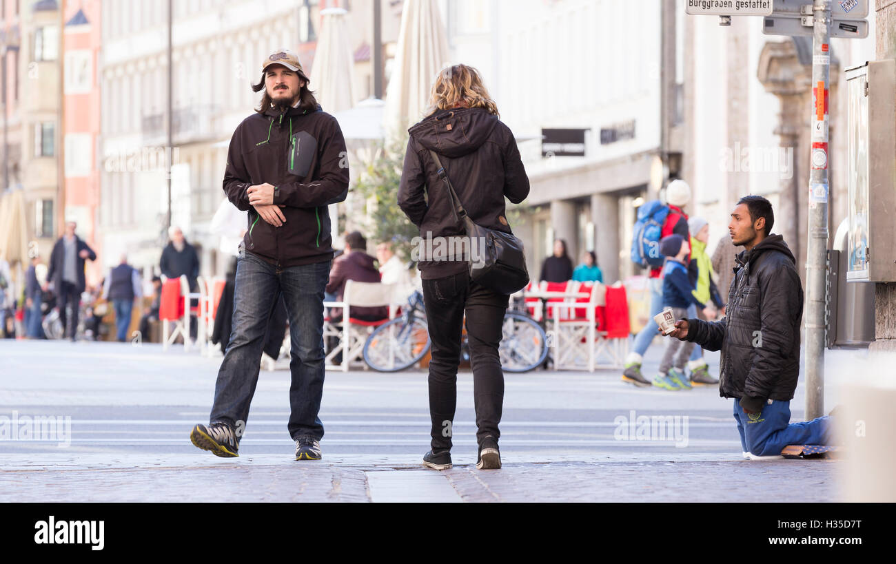 INNSBRUCK, Austria - 1 novembre 2015: rifugiato a mendicare per aiutare nelle strade di Innsbruck con persone che camminano da. Foto Stock