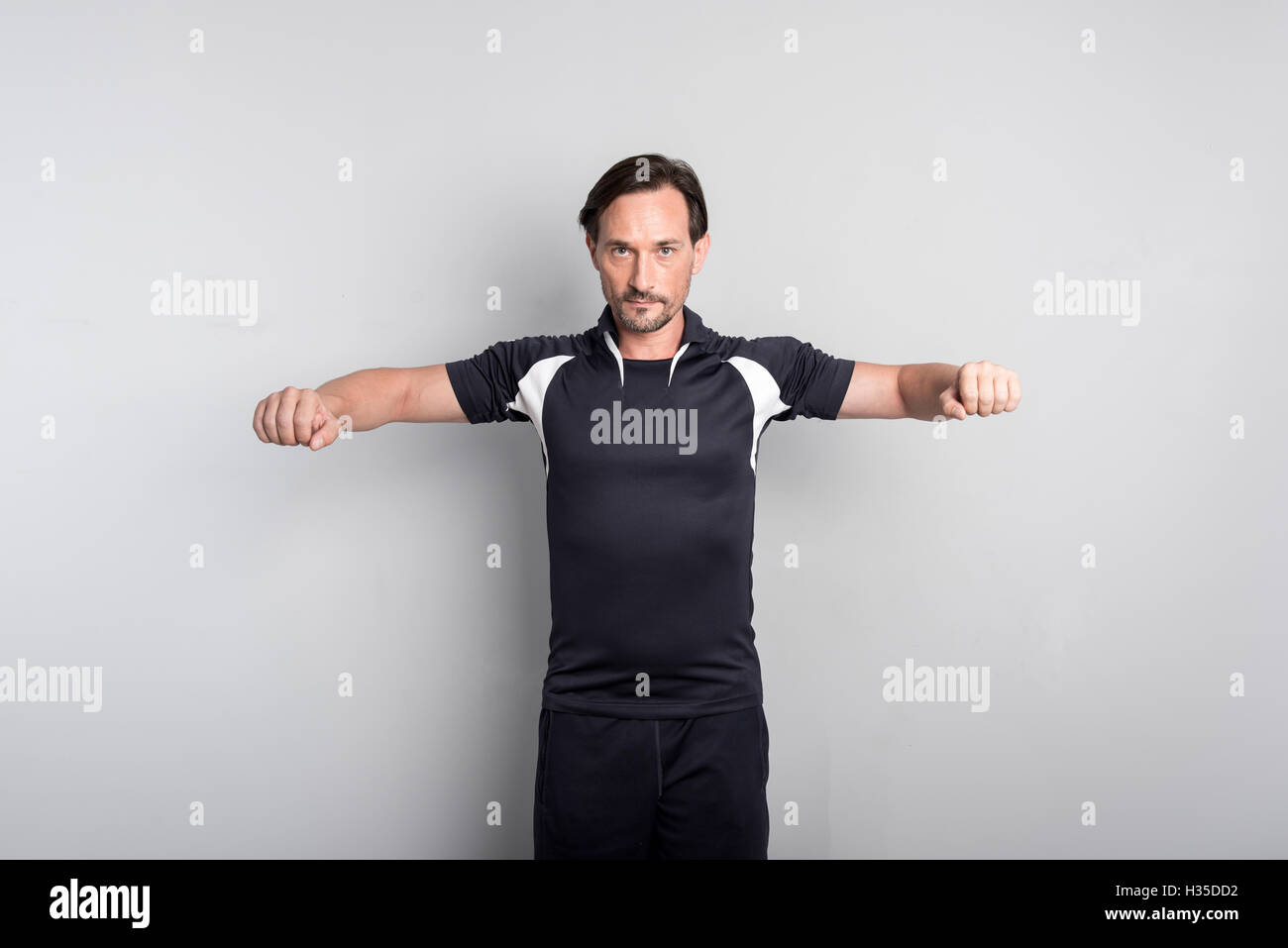 Piacevole sportivo concentrato in piedi isolato su sfondo grigio Foto Stock