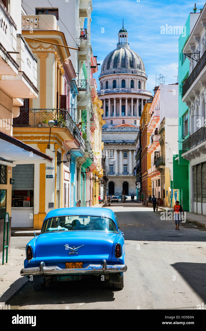 Una classica macchina parcheggiata sulla strada, gli edifici coloniali con l'ex Palazzo del Parlamento, l'Avana, Cuba, West Indies, dei Caraibi Foto Stock
