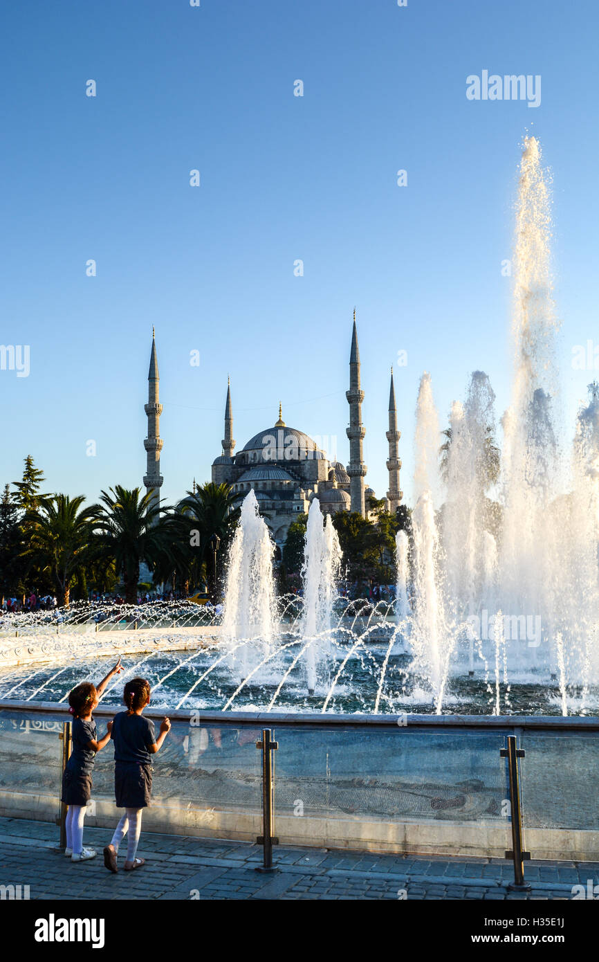 Due giovani ragazze turche rivolto verso la Moschea Blu, l'UNESCO, con fontane in primo piano, Istanbul, Turchia Foto Stock