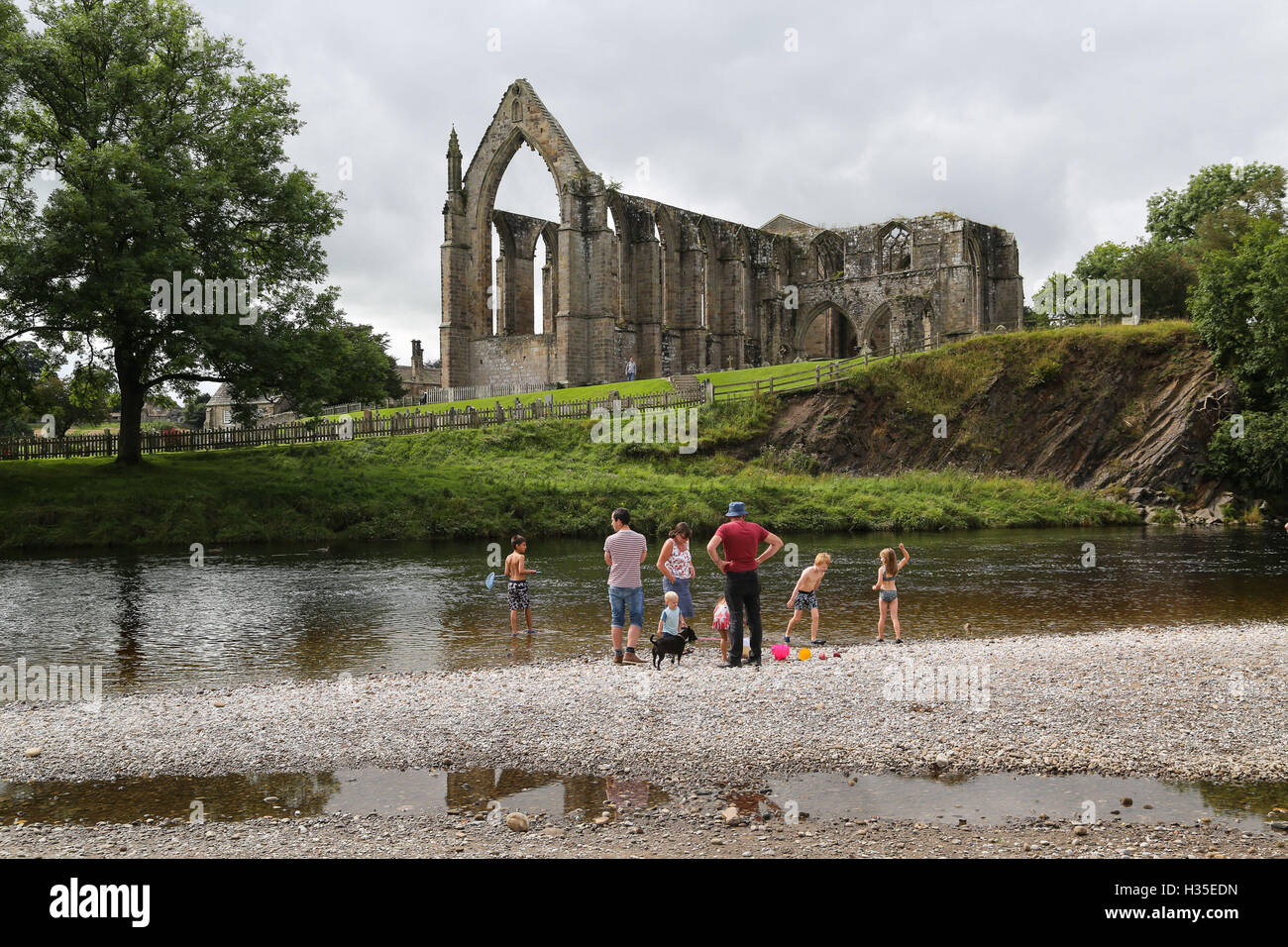 Trippers giorno godetevi il sole e temperature calde accanto al fiume Wharfe a Bolton Abbey vicino a Skipton in North Yorkshire. Foto Stock