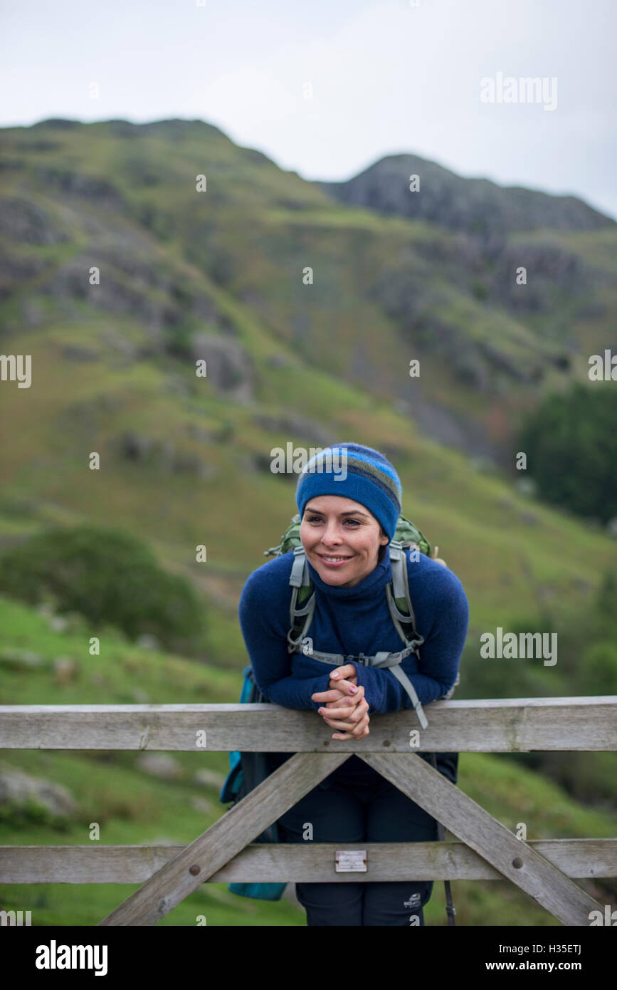 Una donna si appoggia su un cancello in grande Langdale valley nel distretto del lago, Cumbria, England, Regno Unito Foto Stock