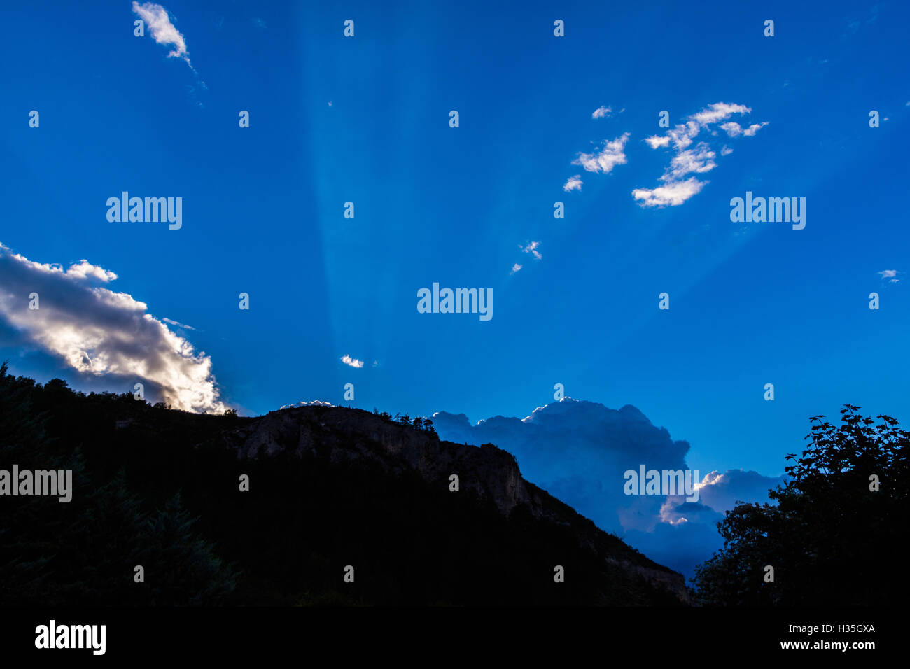Raggi Suns lucenti oltre le nuvole e montagne, crepuscolari, meteo Foto Stock