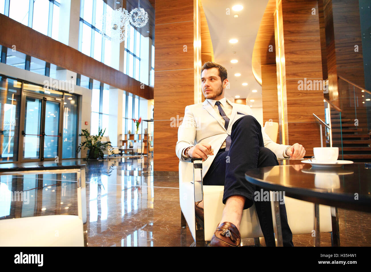 Felice giovane impreditore seduti sul divano nella hall hotel Foto Stock