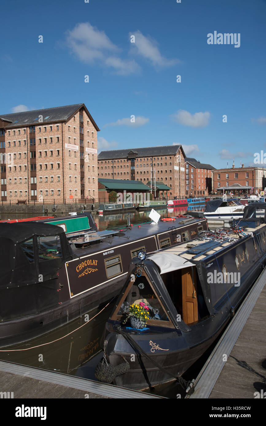 Gloucester Docks Gloucestershire England Regno Unito. Narrowboats ormeggiato con uno sfondo di rifornire i magazzini nella vecchia zona del dock Foto Stock