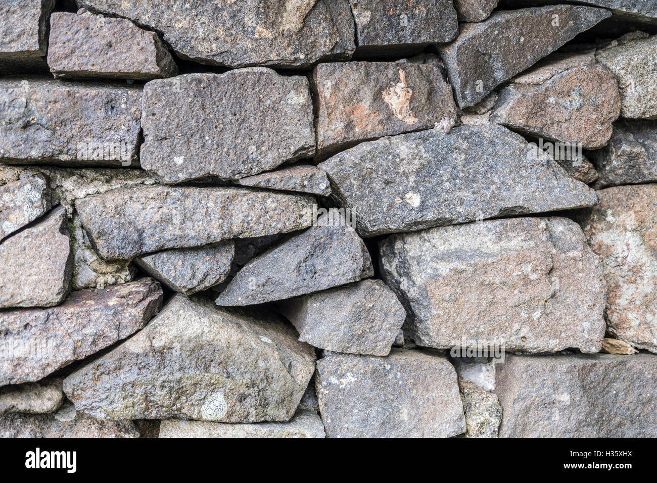 Antico muro di pietra sapientemente costruito con diverse forme di rocce grigie per fornire la texture di sfondo Foto Stock