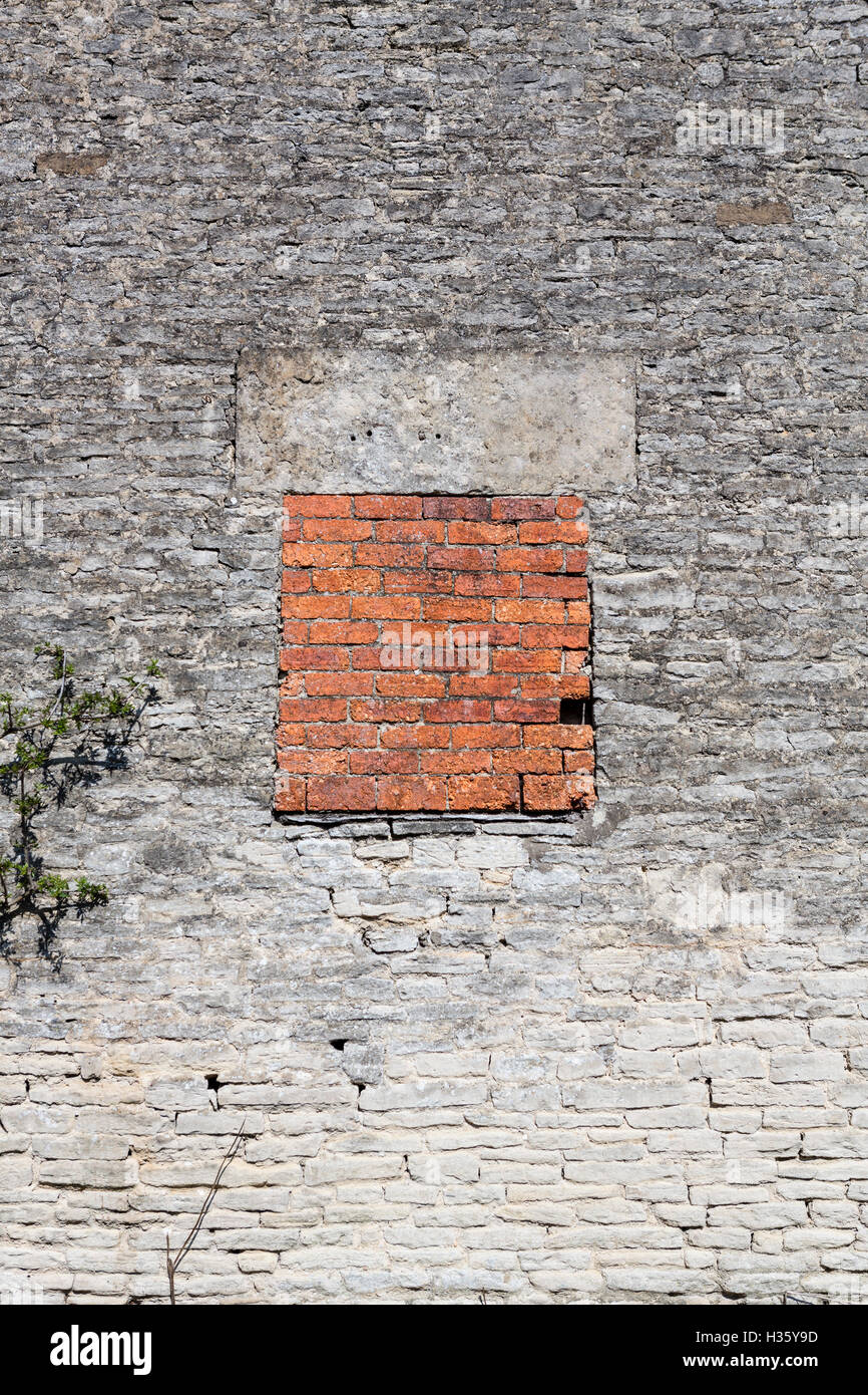 Una murata finestra, mattoni rossi in un antico muro di pietra. Foto Stock