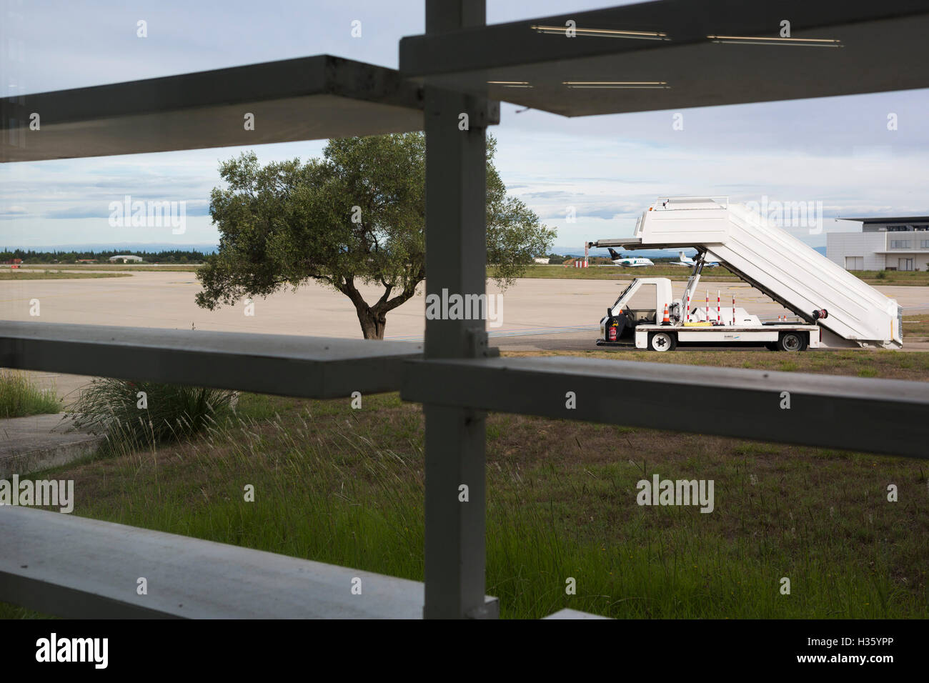 Vista attraverso un aeroporto partenza finestra lounge ay Nimes in Francia per il vuoto e la catenaria airfield. Foto Stock