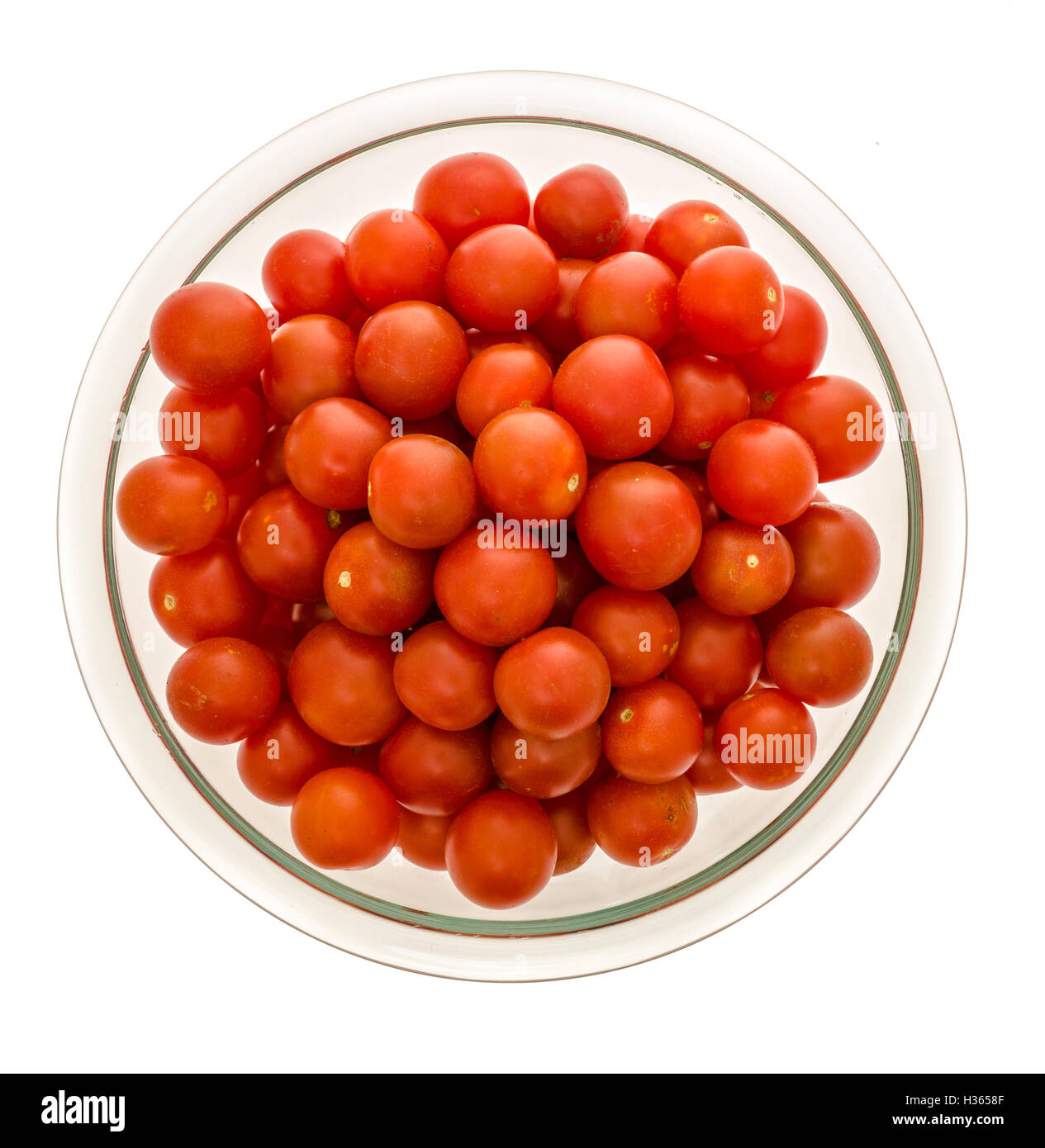 Colpo verticale di pomodori ciliegia in una chiara ciotola di vetro isolato su un background Foto Stock