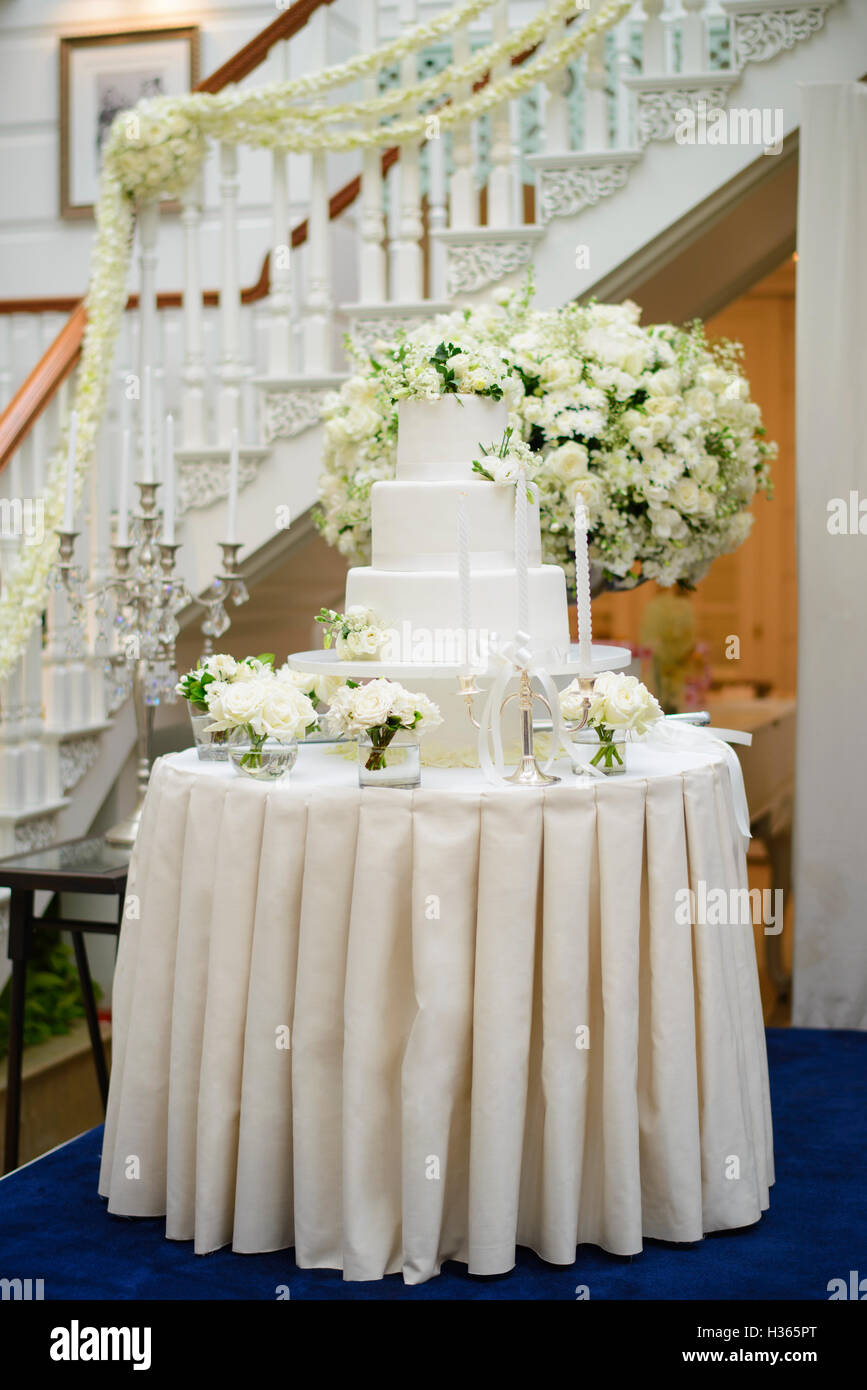 Torta di Nozze circondato da fiori bianchi Foto Stock
