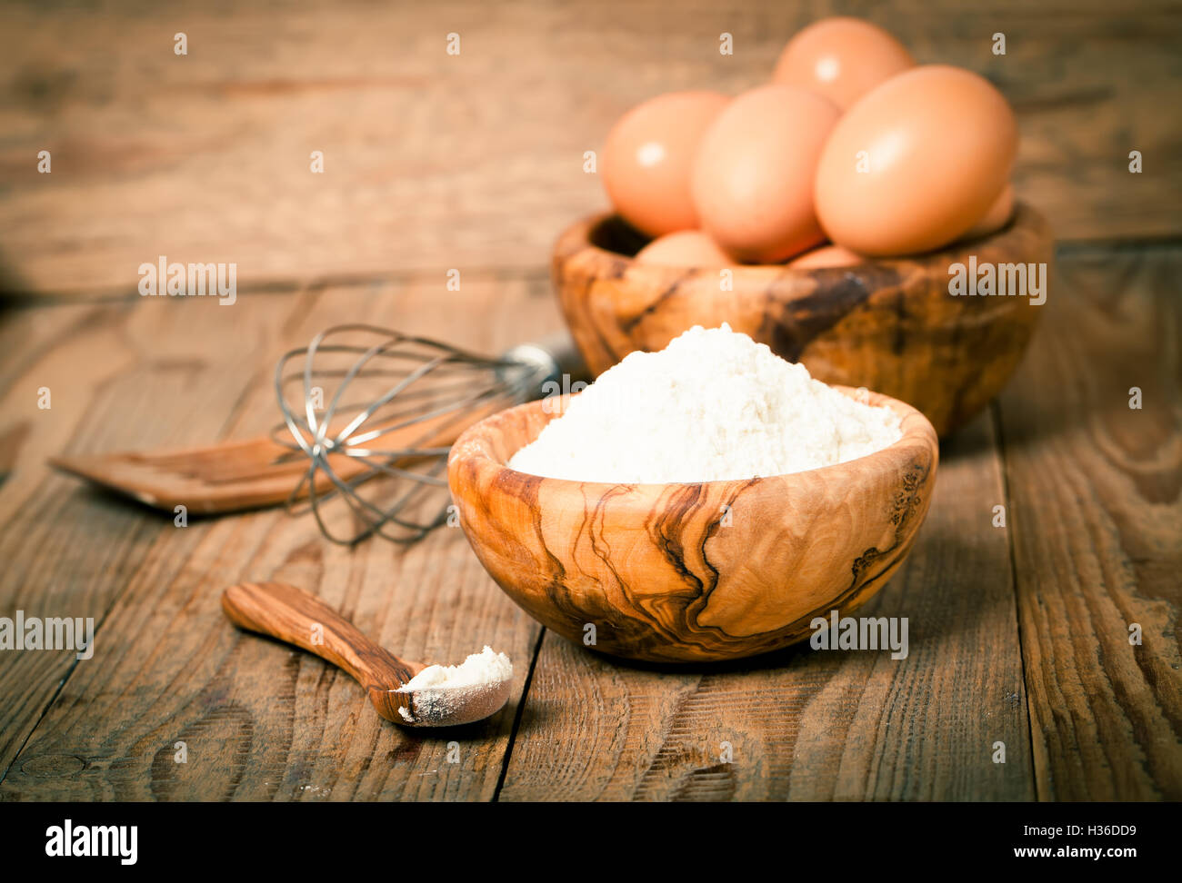 La farina e le uova, gli ingredienti per la cottura. su sfondo di legno Foto Stock