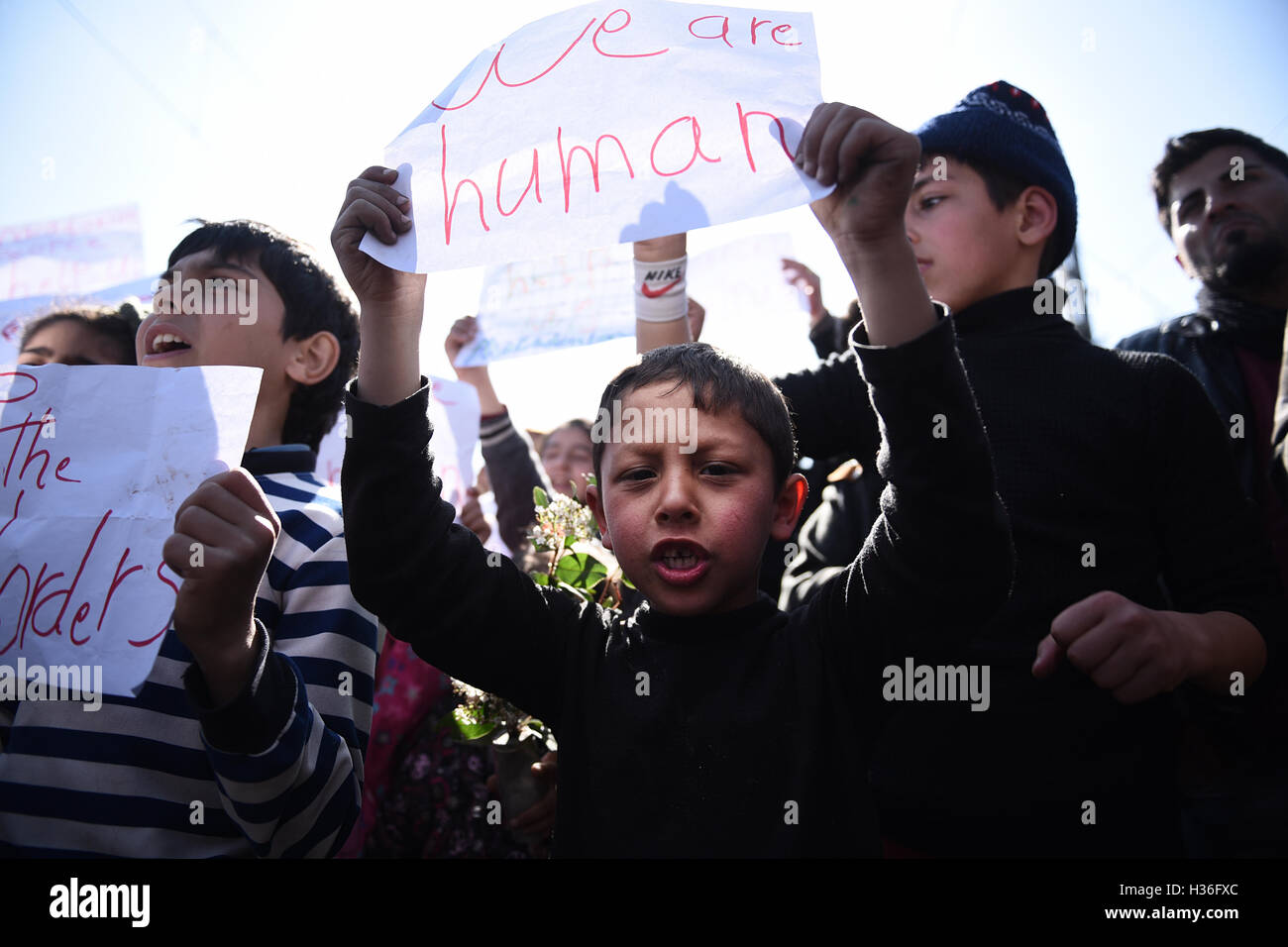 I bambini gridare slogan, come rifugiati e migranti dimostrare esigente per le frontiere dell'Unione europea per aprire, in un campo di rifugiati, a nord del villaggio greco di Idomeni. Migliaia di rifugiati e migranti sono rimasti bloccati per mesi al Greco confine macedone, presso il campo di rifugiati nei pressi del villaggio di Idomeni, fino a quando il governo greco ha deciso di evacuare l'area. Foto Stock