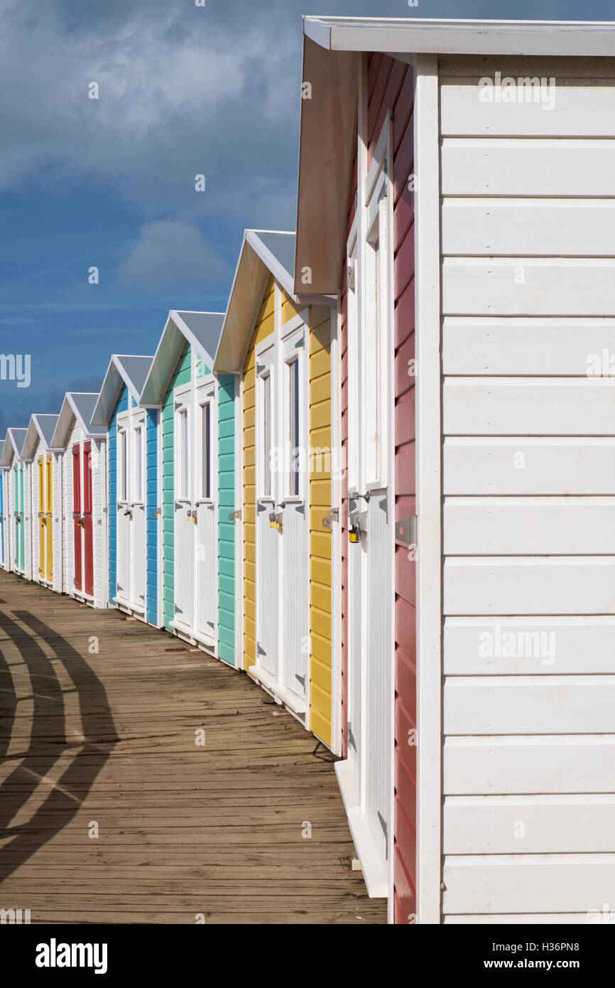 Fila di chalets bloccata fuori stagione e costruito nello stile di quelle che si trovano tradizionalmente in inglese mare Foto Stock