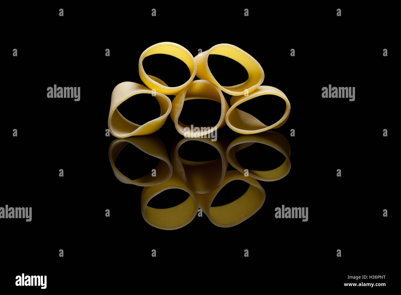 Cinque pezzi di rigatoni pasta organizzato uno sull'altro su un black reflection backround Foto Stock