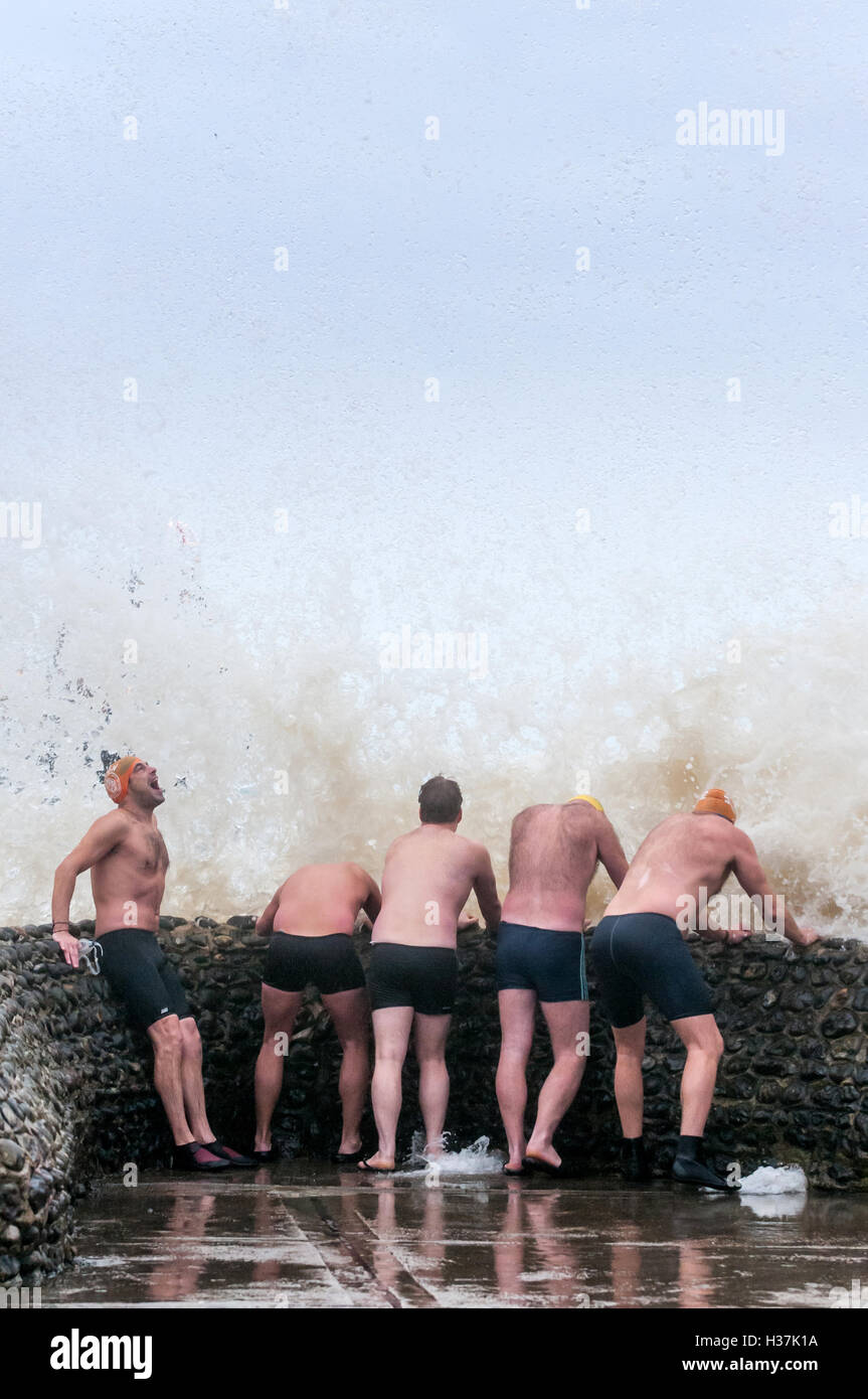 I membri del gruppo Brighton Nuoto Club godono di un 'groyne doccia' quando il mare è troppo pericolosa per nuotare. Foto Stock
