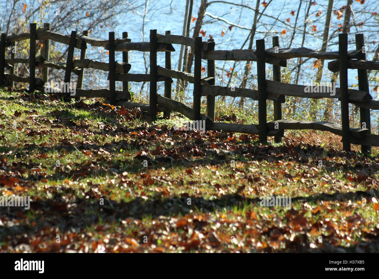 Staccionata in legno confinante con un fiume in autunno Foto Stock