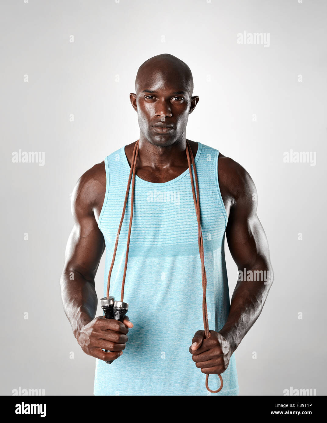 Bel uomo muscoloso con salto con la corda su sfondo grigio. Montare modello africana guardando la fotocamera con corda da salto. Foto Stock