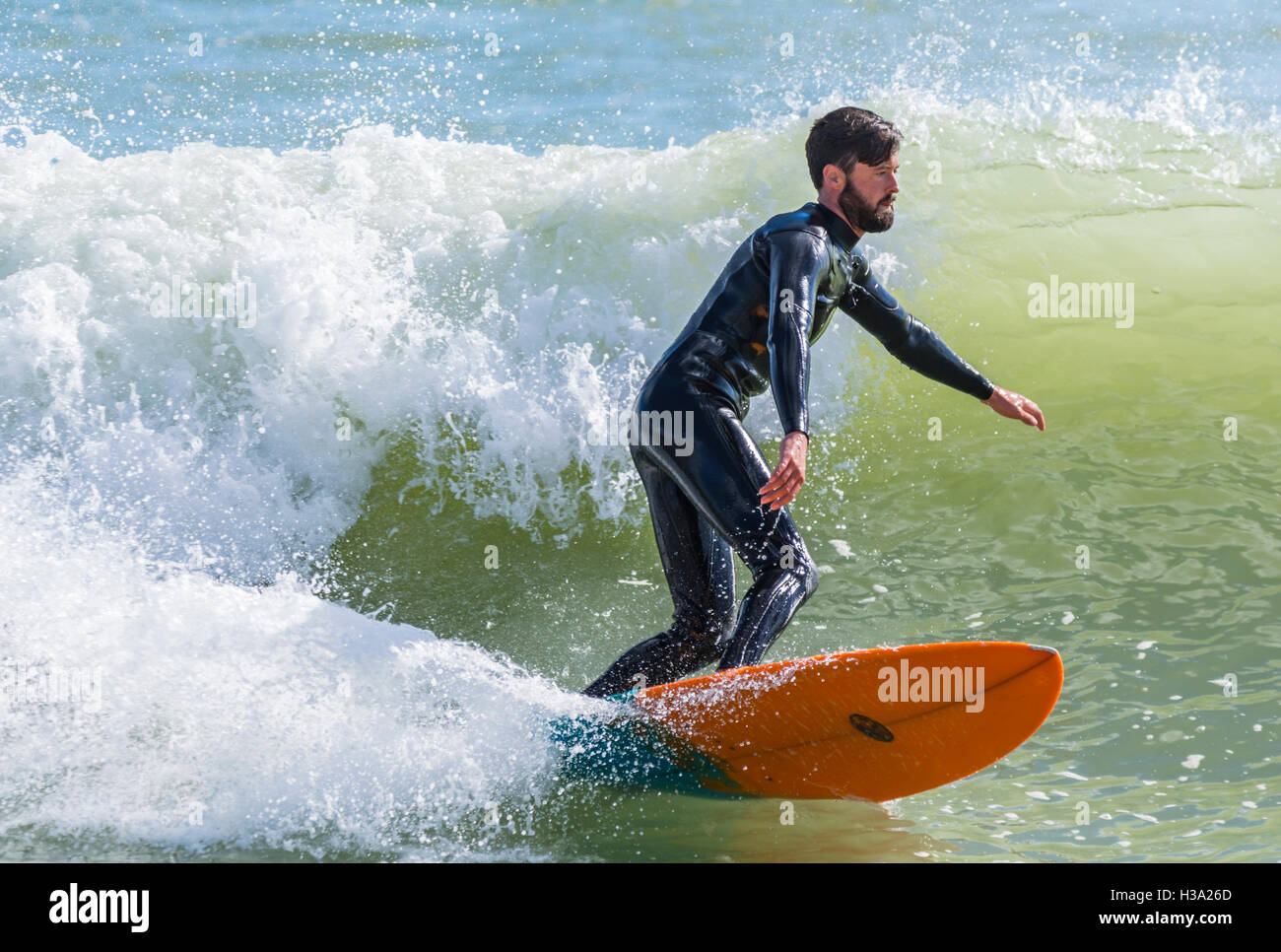 L'uomo surf su una tavola da surf sulle onde del mare. Foto Stock