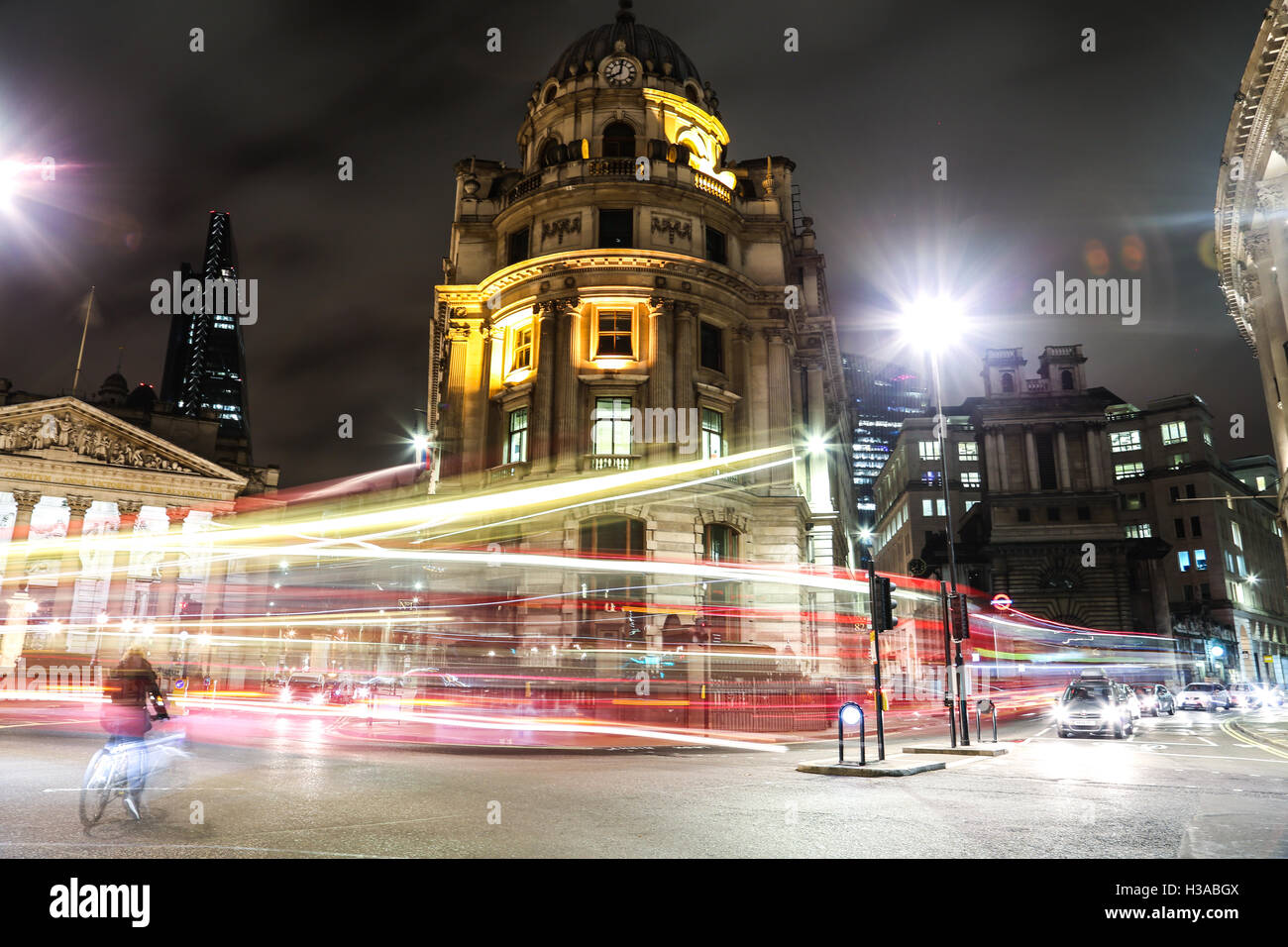 Banca e Monument Station di notte, con un ciclista che fa il suo modo attraverso le strisce di semafori. Foto Stock