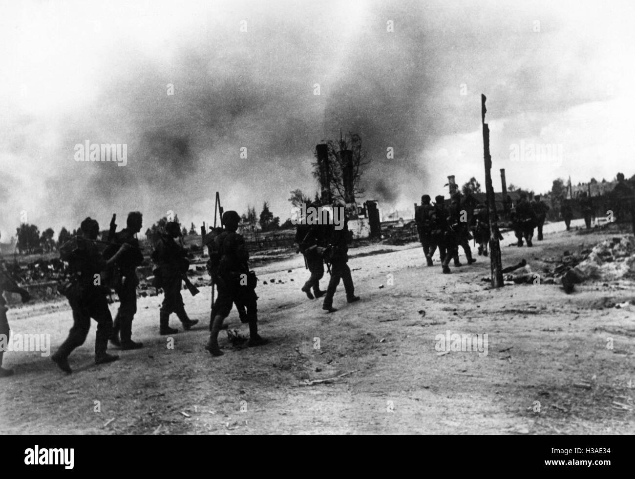 La fanteria tedesca in marcia attraverso un villaggio in rovina, 1941 Foto Stock