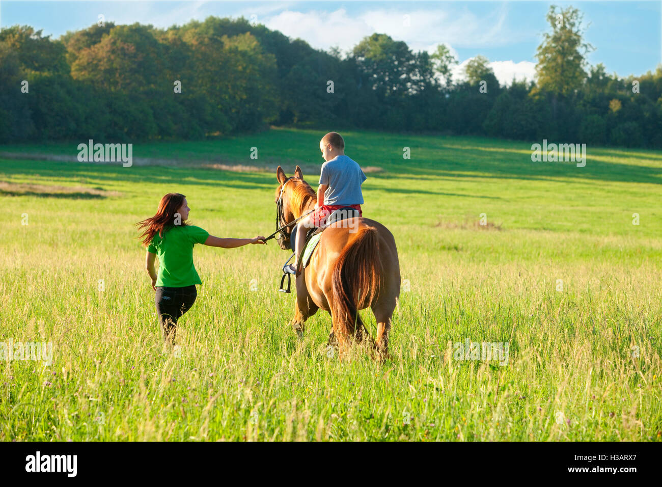 Equitazione lezioni - La donna protagonista di un cavallo con un ragazzo in sella Foto Stock