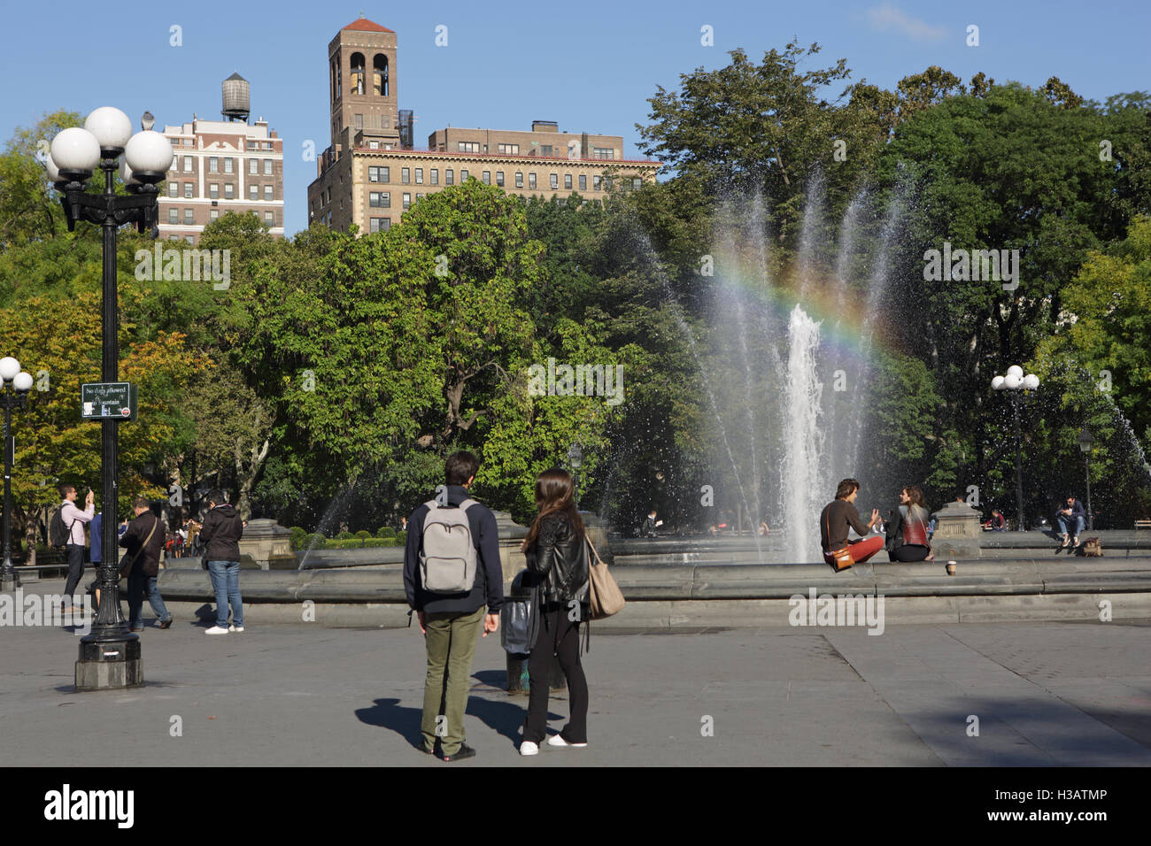 Le persone camminare e parlare accanto alla fontana di Washington Square Park, New York Foto Stock