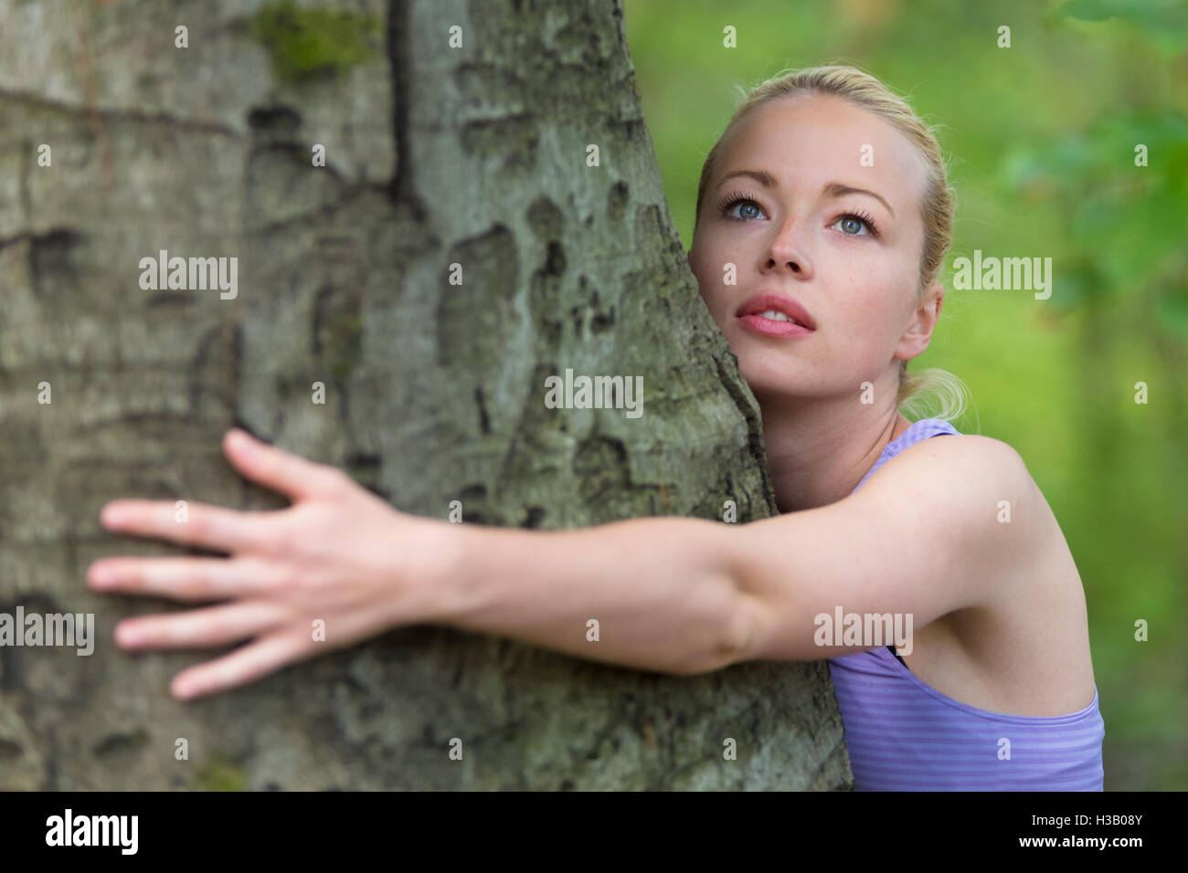 Giovane donna che abbraccia un albero. Foto Stock