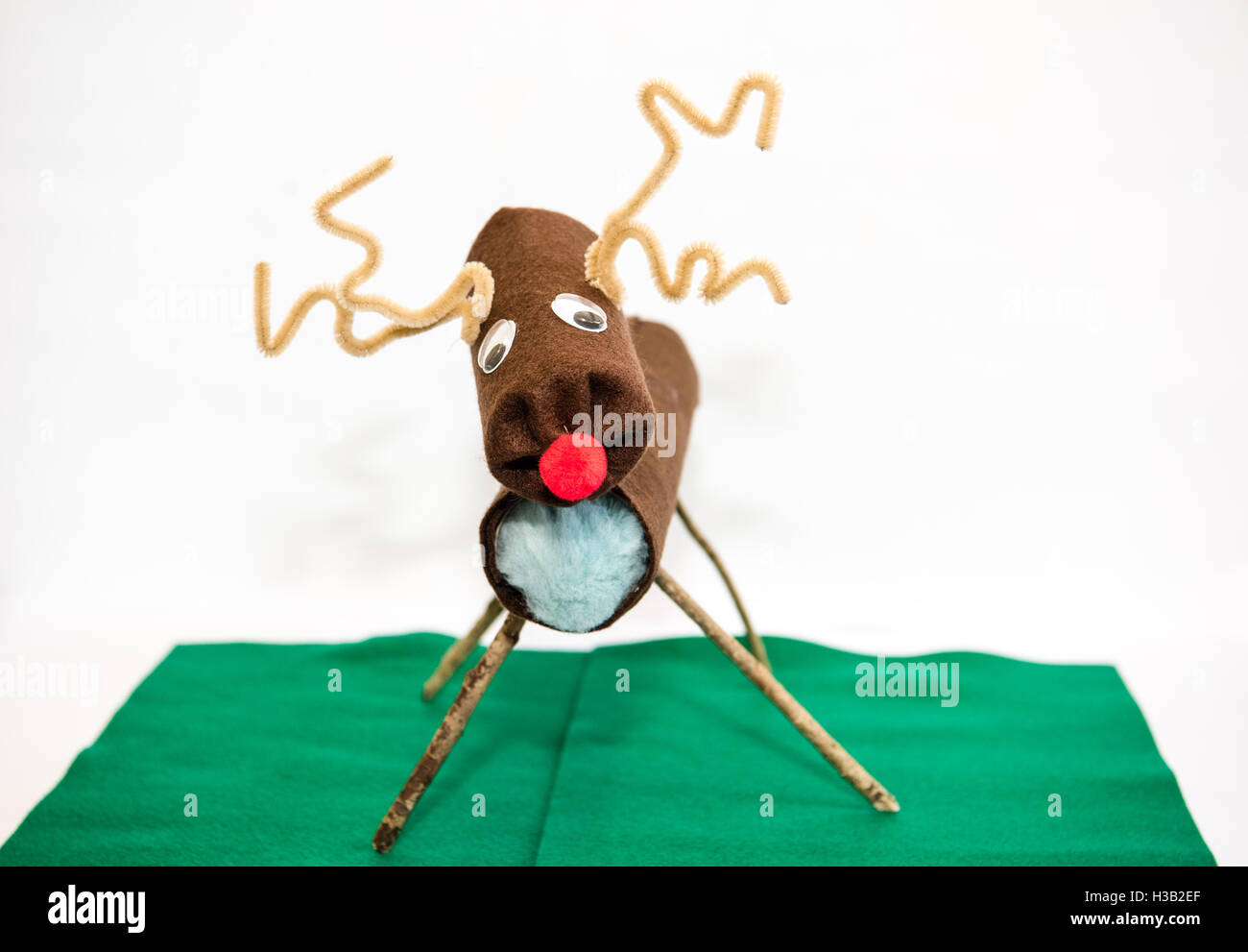 Un divertente wonky artigianale di Rudolph la renna natale decorazione realizzata dal riciclaggio di rotoli di carta igienica e pulitori della tubazione su un po' di feltro verde Foto Stock