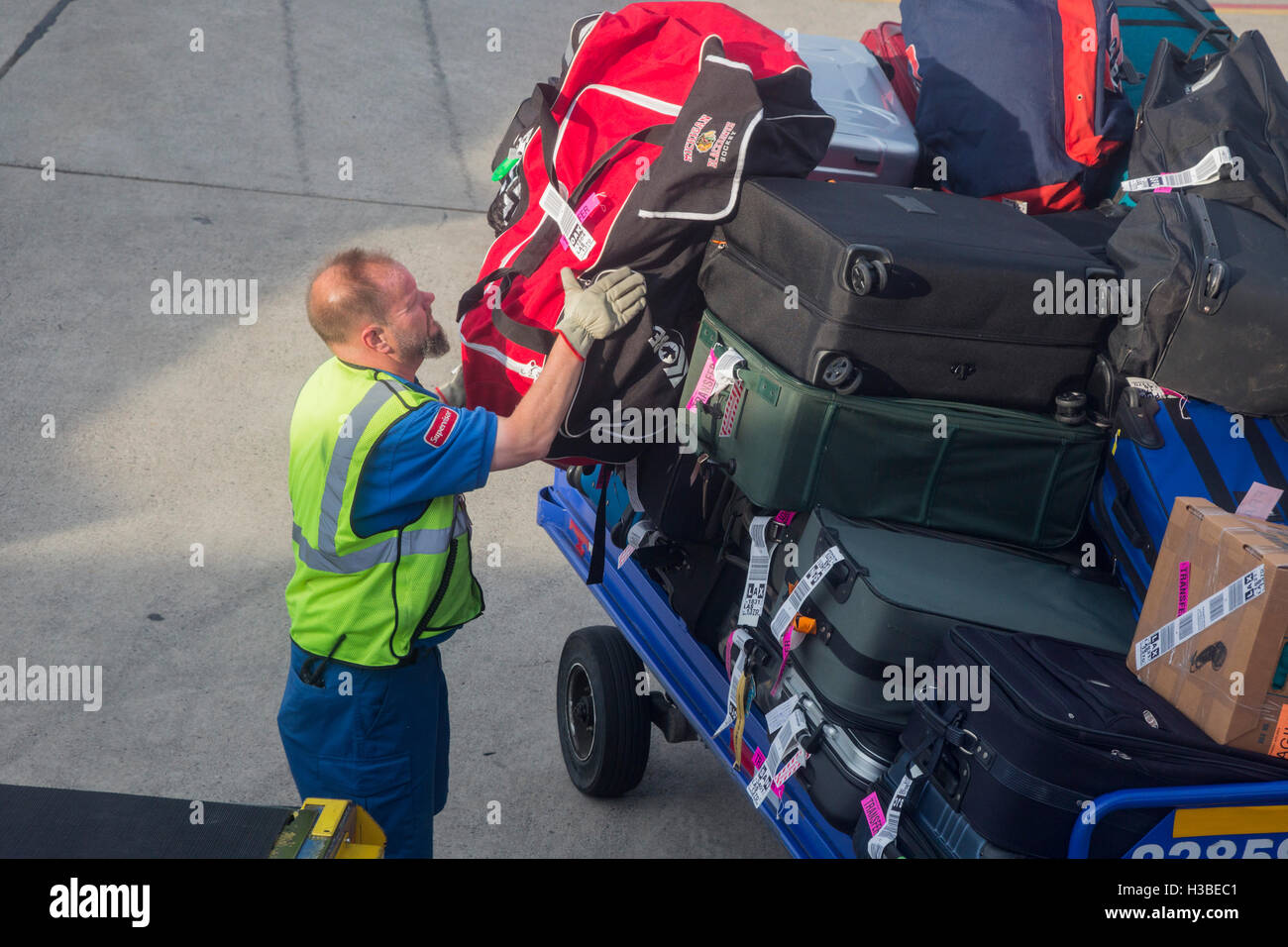 Detroit, Michigan - un lavoratore bagaglio i carichi su di un getto a Detroit Metro Airport. Foto Stock