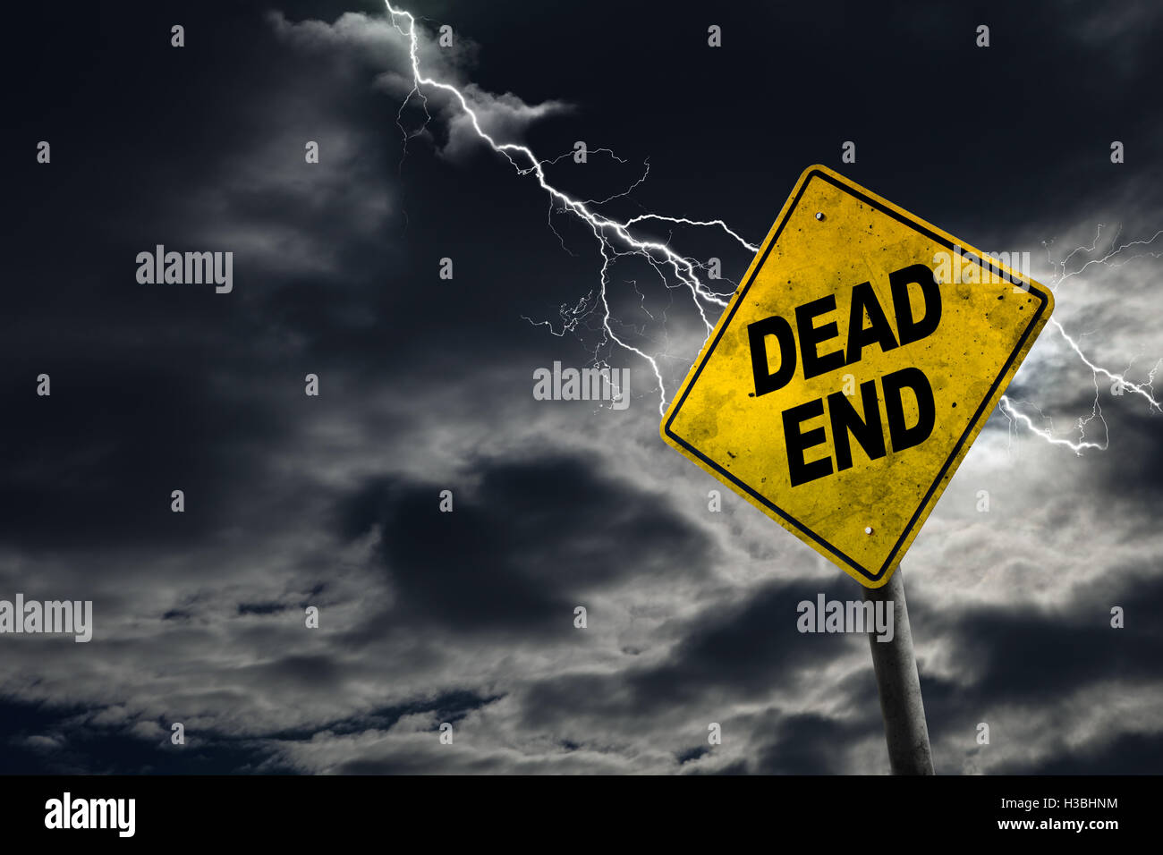 Dead End road sign contro un sfondo tempestoso con lampi e copia di spazio. Sporco e cartello angolato aggiunge al dramma. Foto Stock