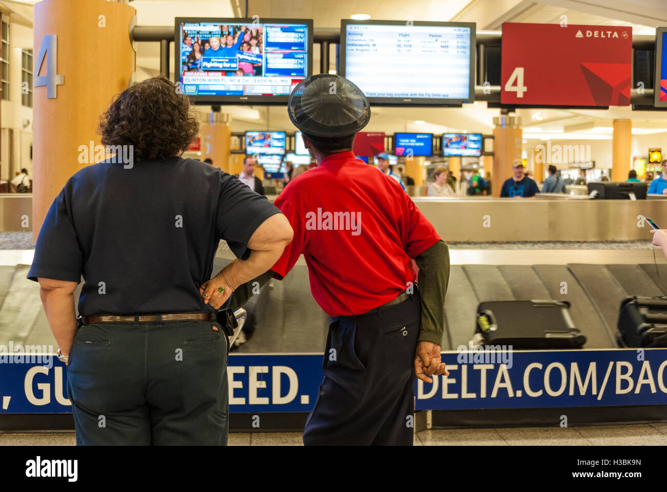 Atlanta Airport dipendenti guarda elezione primaria risultati per Hillary Clinton campagna presidenziale da Delta il reclamo bagagli. Foto Stock