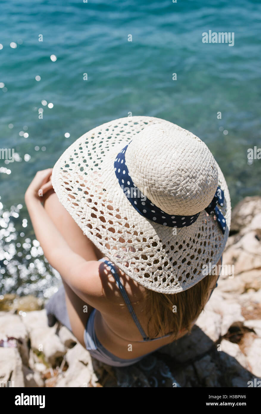 Donna con cappello seduto sulla spiaggia in riva al mare Foto stock - Alamy