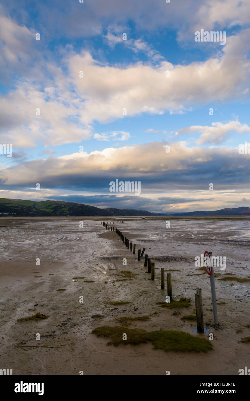 Una fila di posti che portano verso l'orizzonte al tramonto in poi Dyfi estuary, Wales, Regno Unito Foto Stock