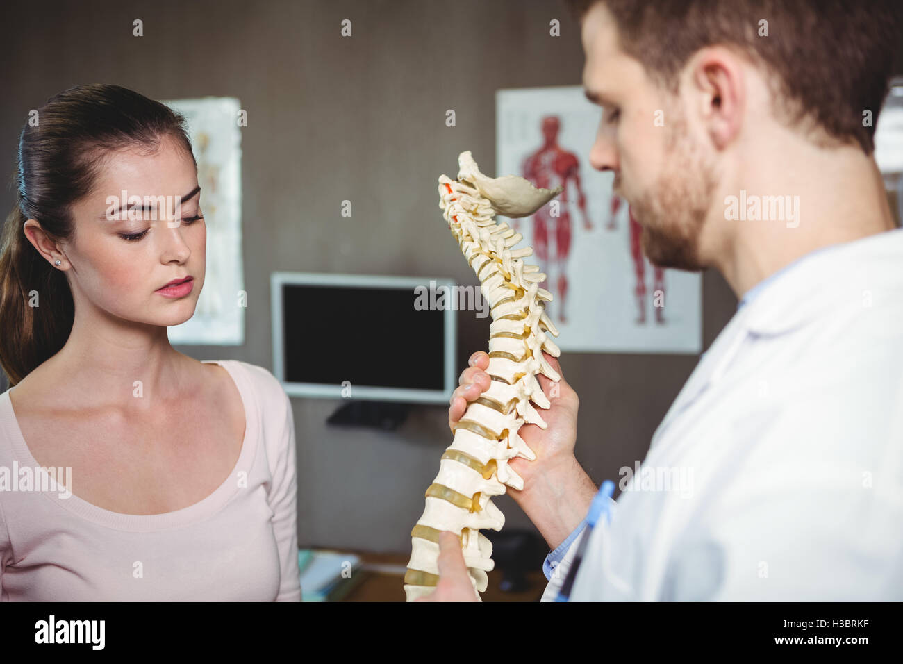 Fisioterapista che spiega la spina dorsale per pazienti di sesso femminile Foto Stock