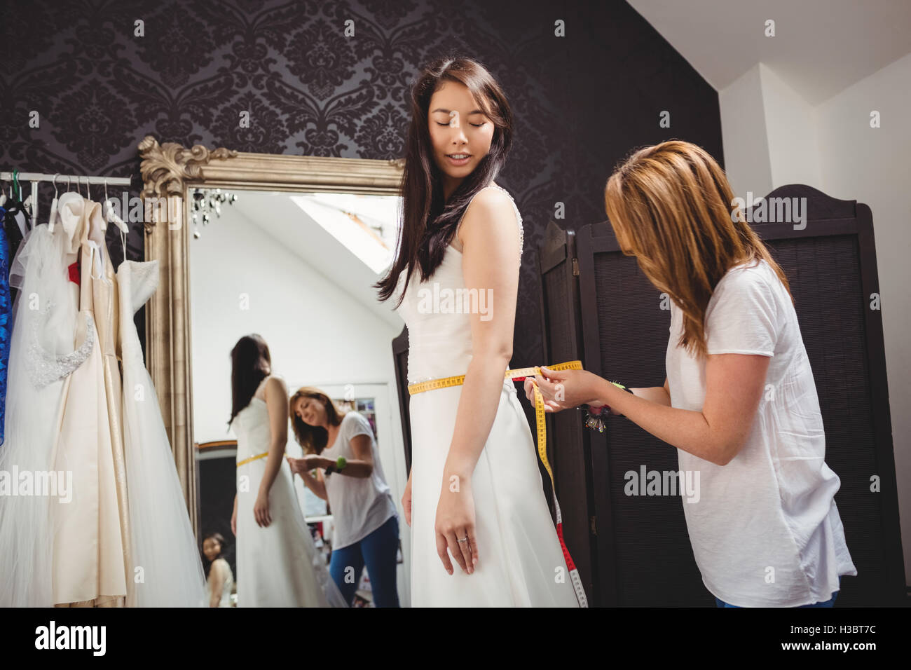 Donna cercando in abito da sposa con il contributo di designer creativo Foto Stock