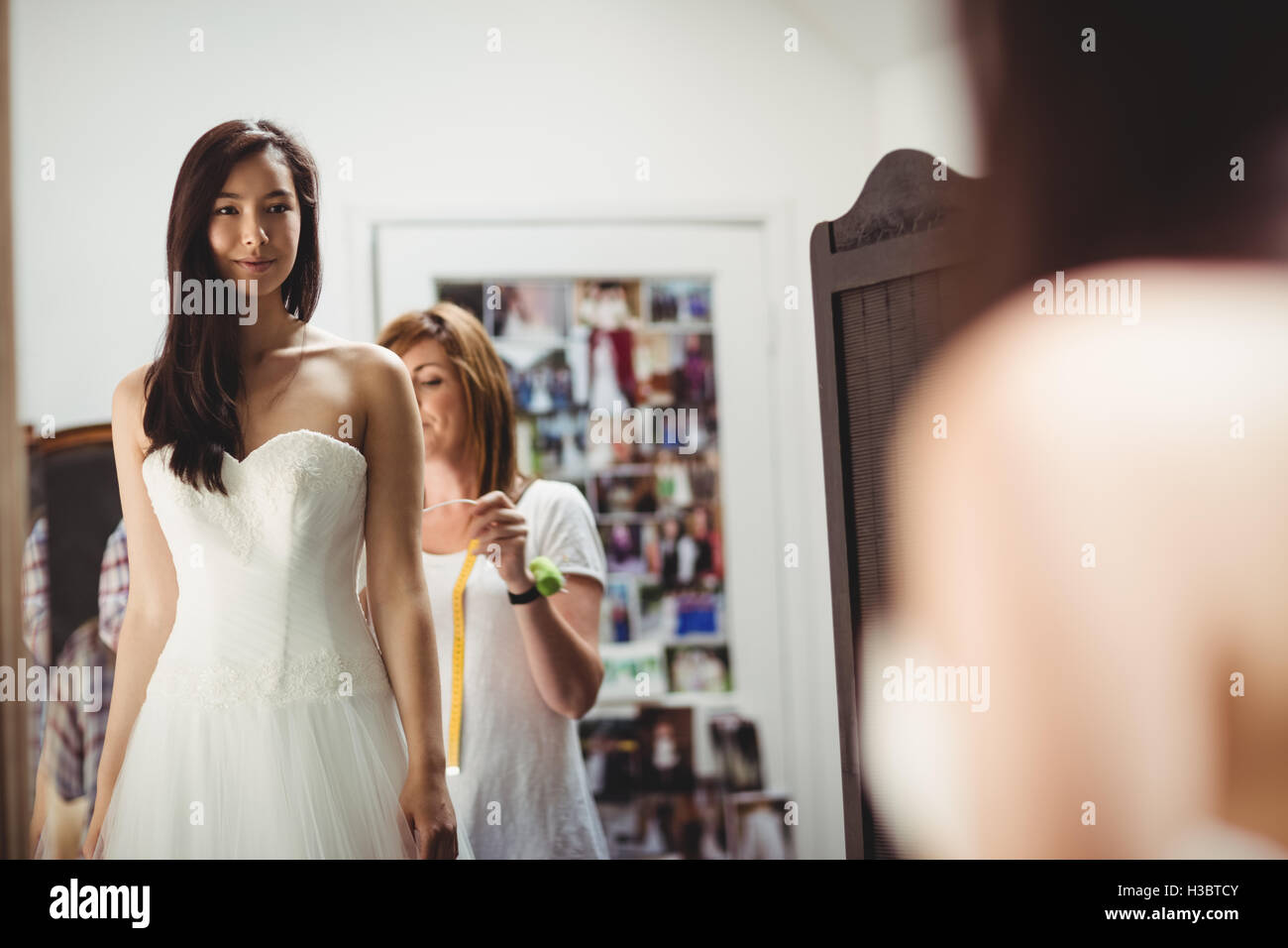 Donna cercando in abito da sposa con il contributo di designer creativo Foto Stock