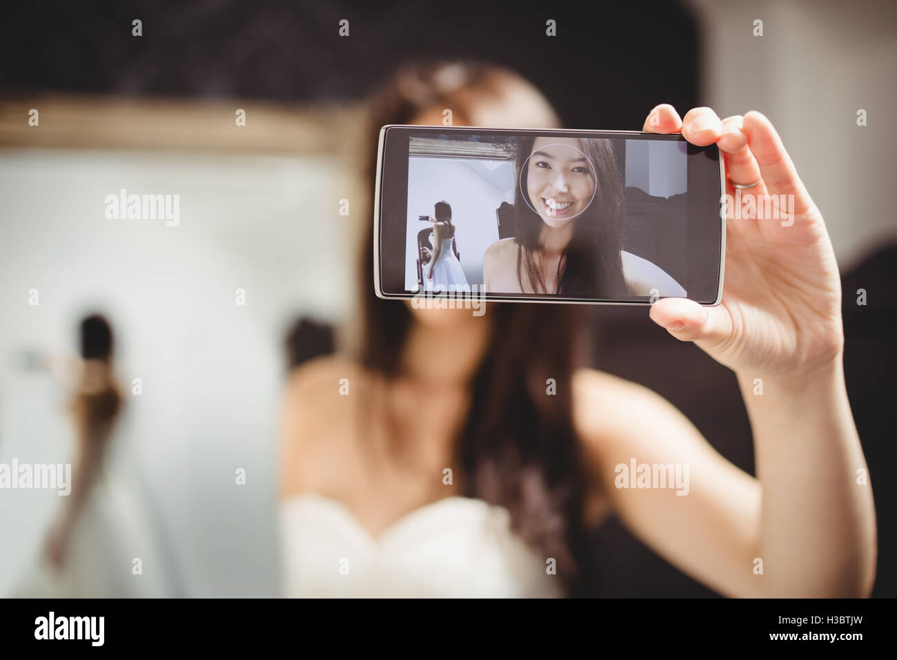 Donna prendendo selfie durante il tentativo su di un abito da sposa Foto Stock
